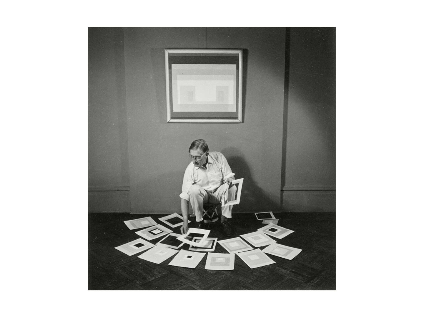 A photograph by Rudy Burckhardt of Josef Albers working in his studio, dated 1950.