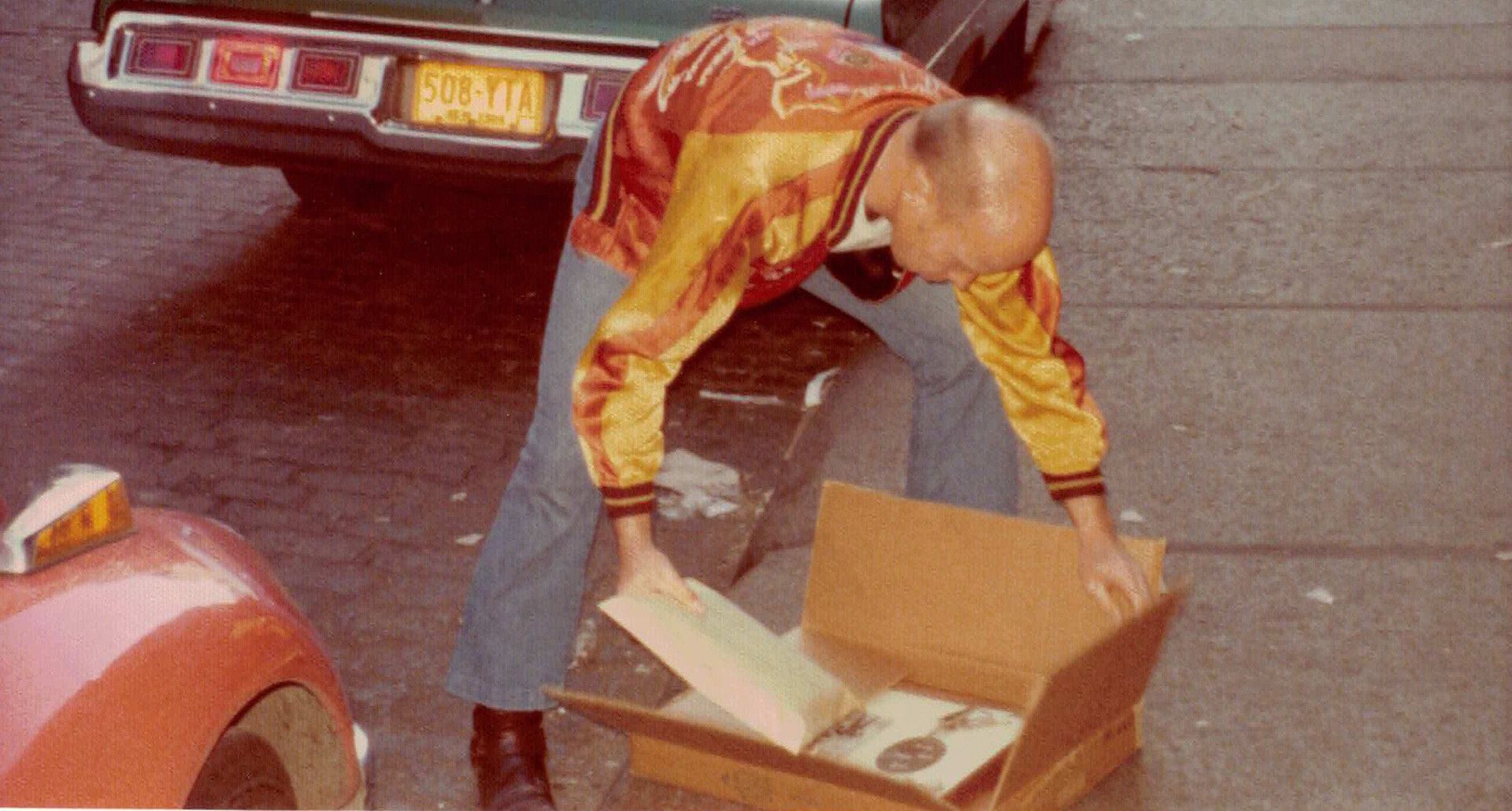 A photo of Ray Johnson in the street with his collage works in 1976.