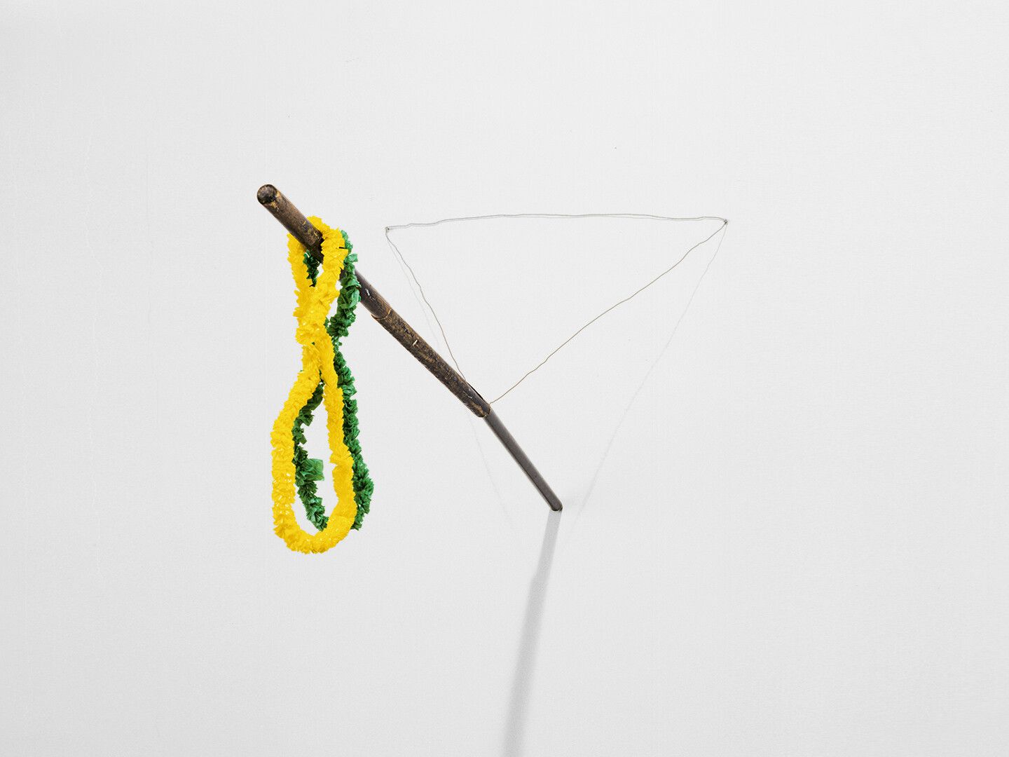 A wooden broomsticks, enamel paint, wire, and plastic leis sculpture by Al Taylor, titled, Layson a Stick, dated 1989.