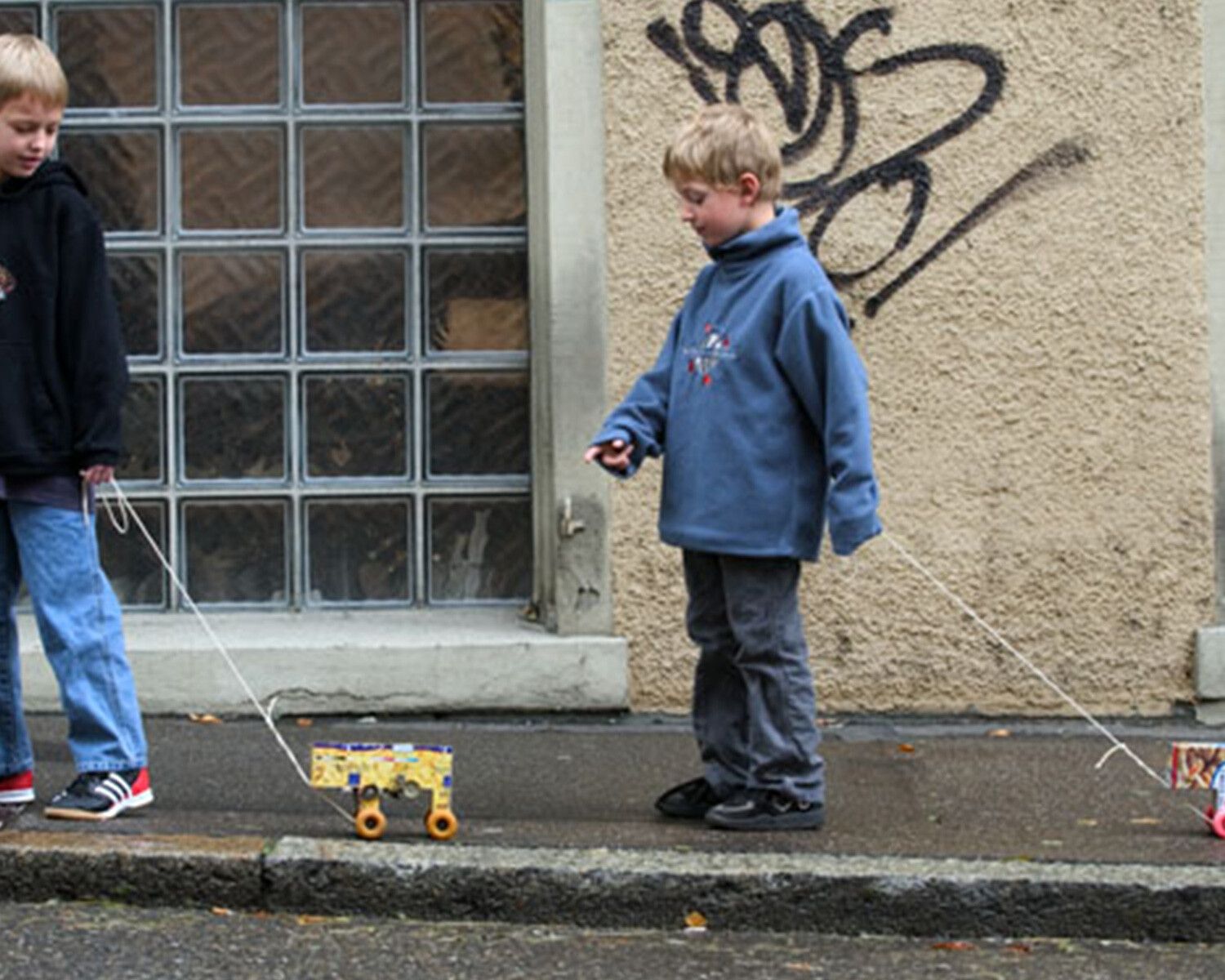 Two children, each with a Francis Alÿs Ghetto Collector, walking through the streets of Zurich, 2003. Courtesy Luma Living Archives, Arles