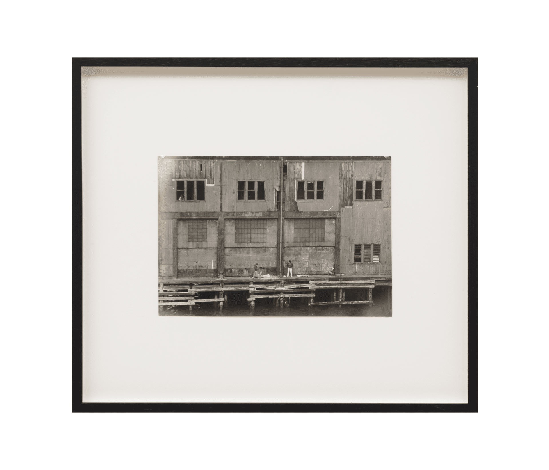 A photograph by Alvin Baltrop, titled The Piers (exterior with four figures), dated 1975-1986.