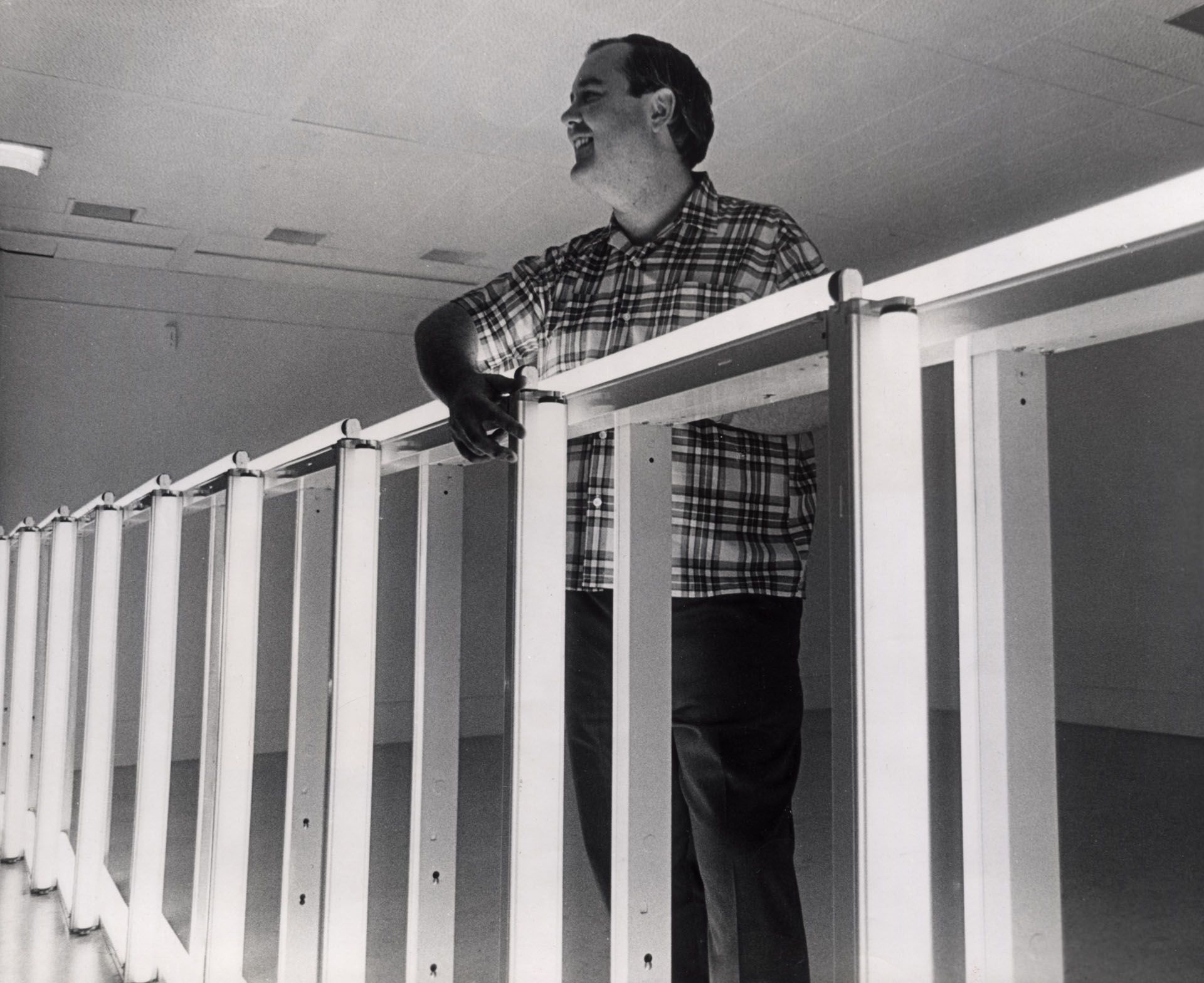 A photo of Dan Flavin installing his exhibition fluorescent light, etc, from Dan Flavin at the National Gallery of Canada, Ottawa, 1969.