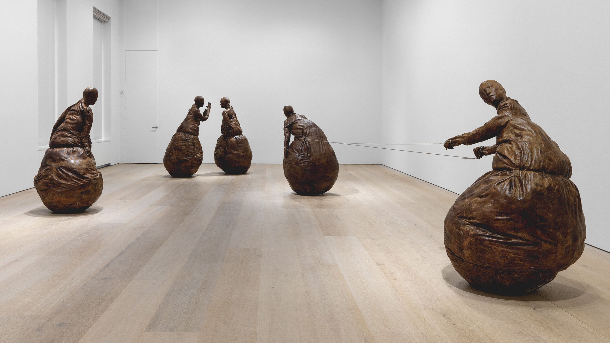 An installation of five bronze and steel cable sculptures by Juan Muñoz, titled Conversation Piece, dated 2001.
