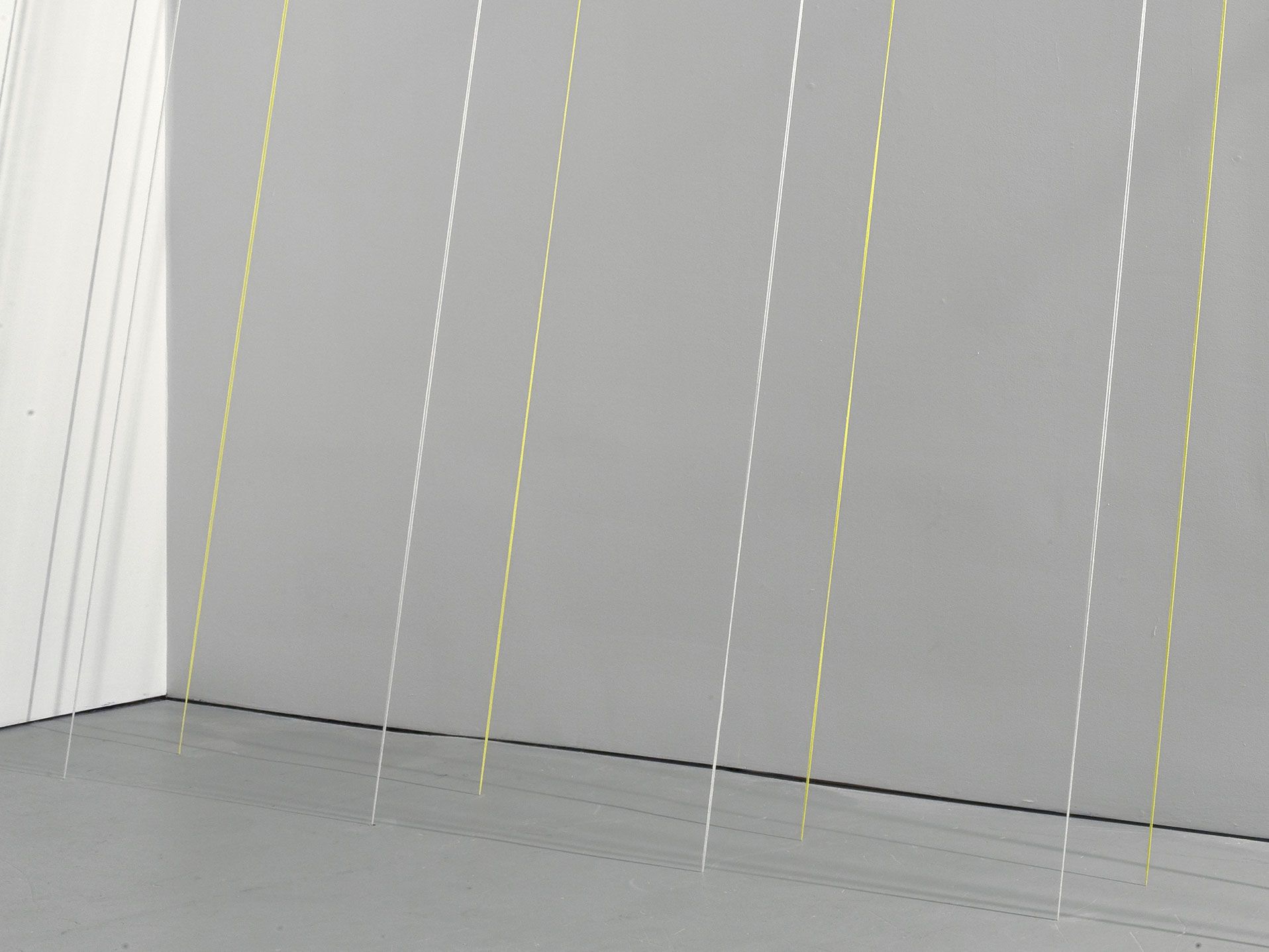 A detail view of a white and yellow acrylic yarn sculpture by Fred Sandback titled Untitled (Eighteen-part Leaning Construction), dated 1988. 