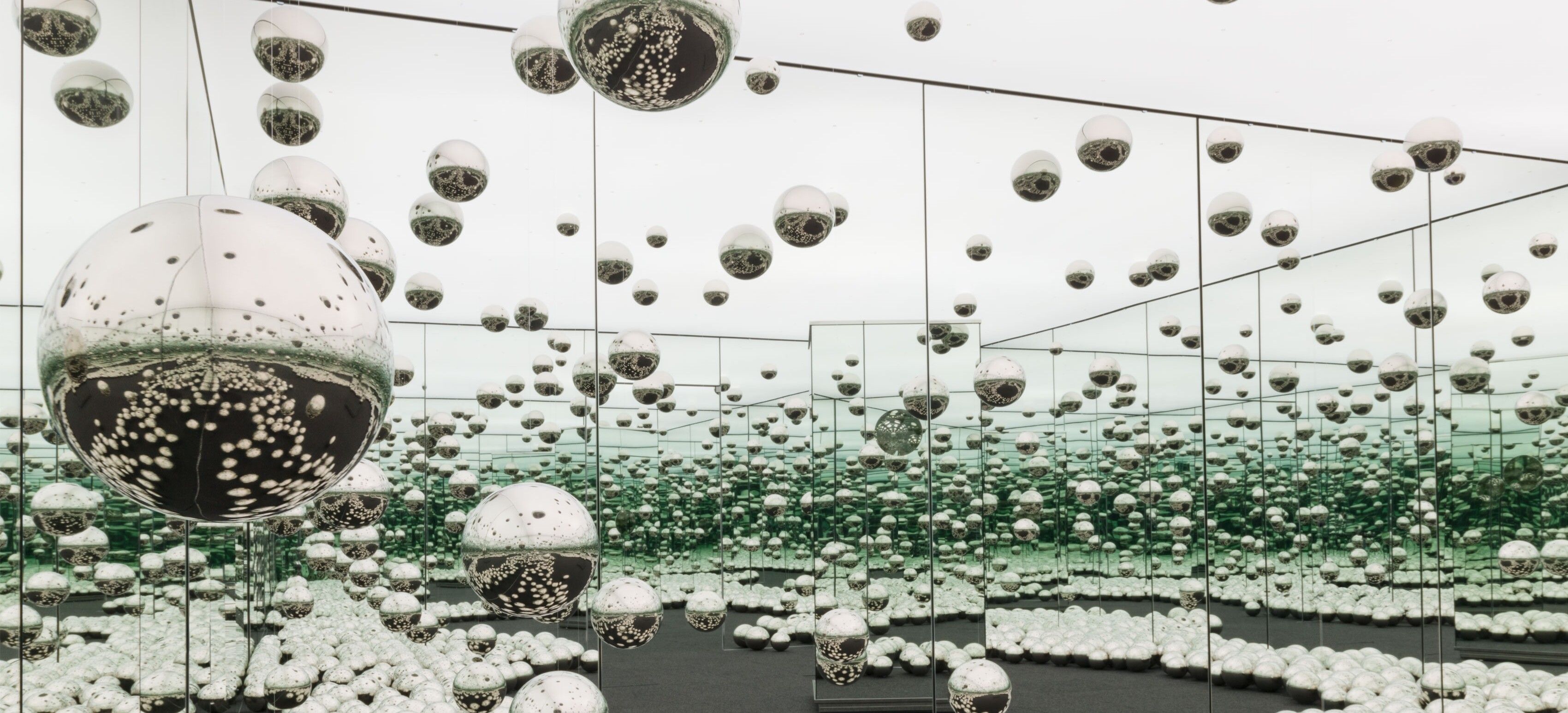 An experiential installation by Yayoi Kusama, comprised of mirrors, wood, LED lighting system, metal, and carpeting, titled Infinity Mirrored Room - Let's Survive Forever, dated 2017.
