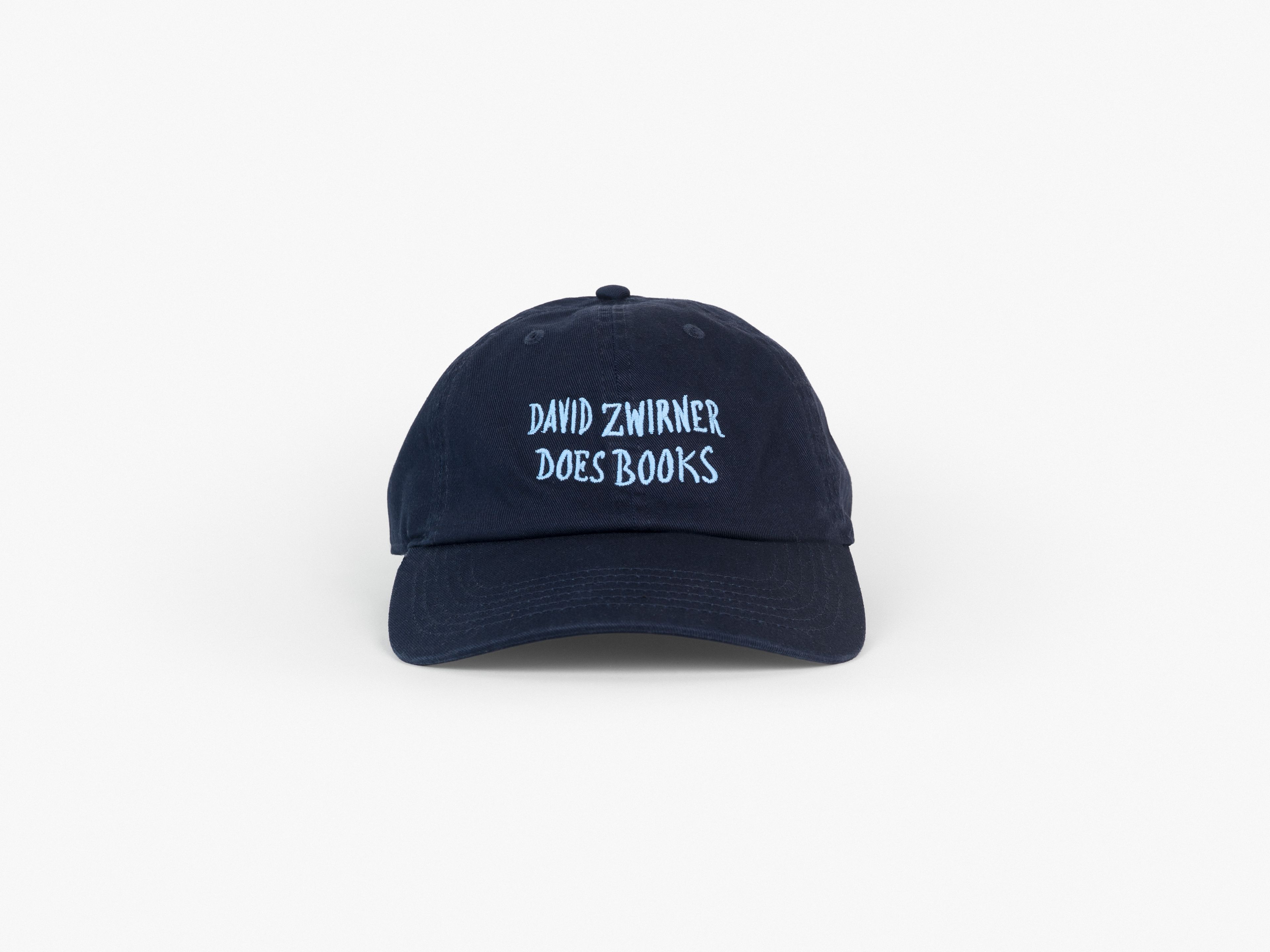A classic six-panel cap in navy cotton twill, featuring embroidered handwriting by Marcel Dzama reading "David Zwirner Does Books"