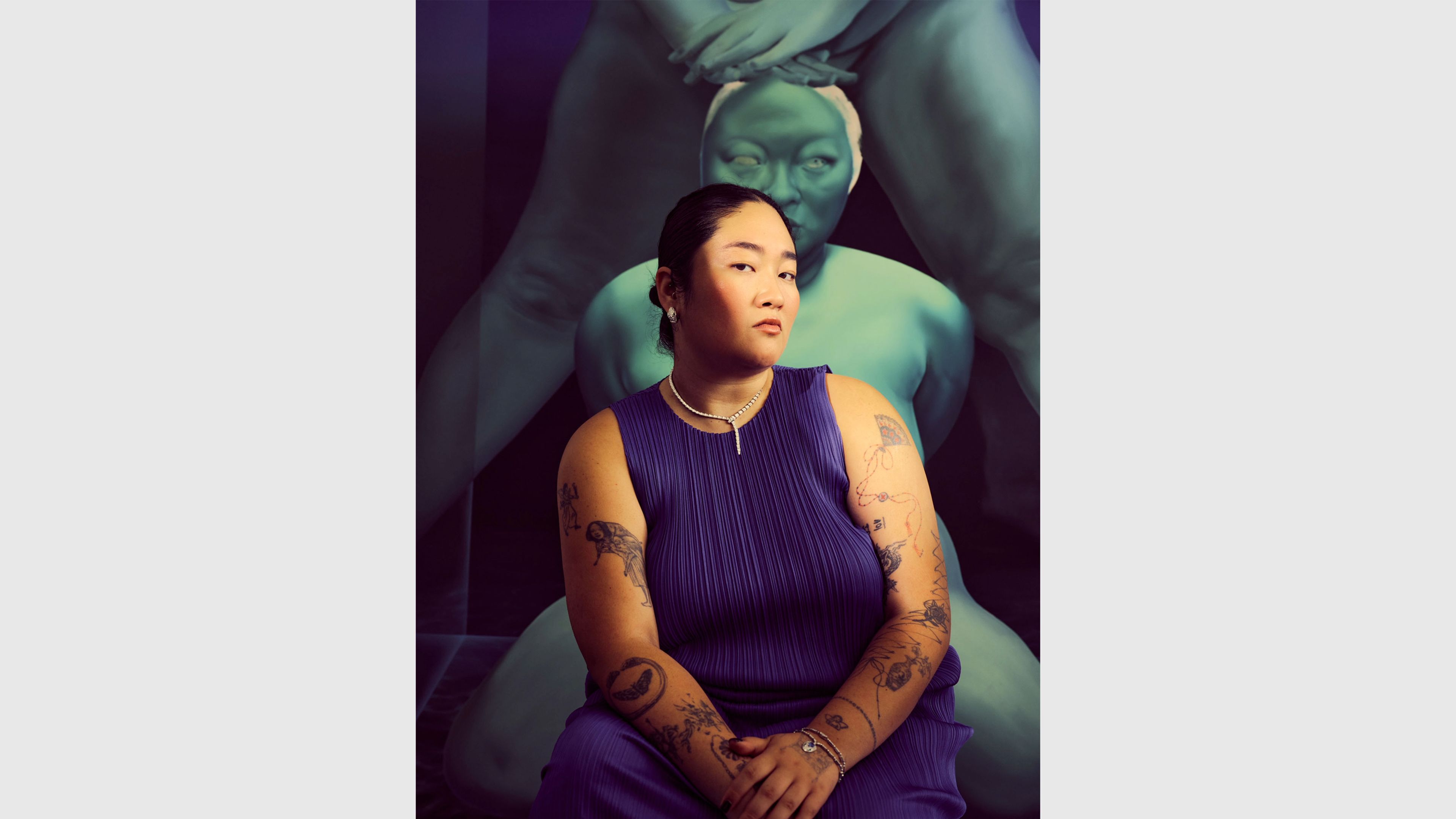 A color photo of Sasha Gordon in front of a large-scale teal figurative artwork, dated 2026.