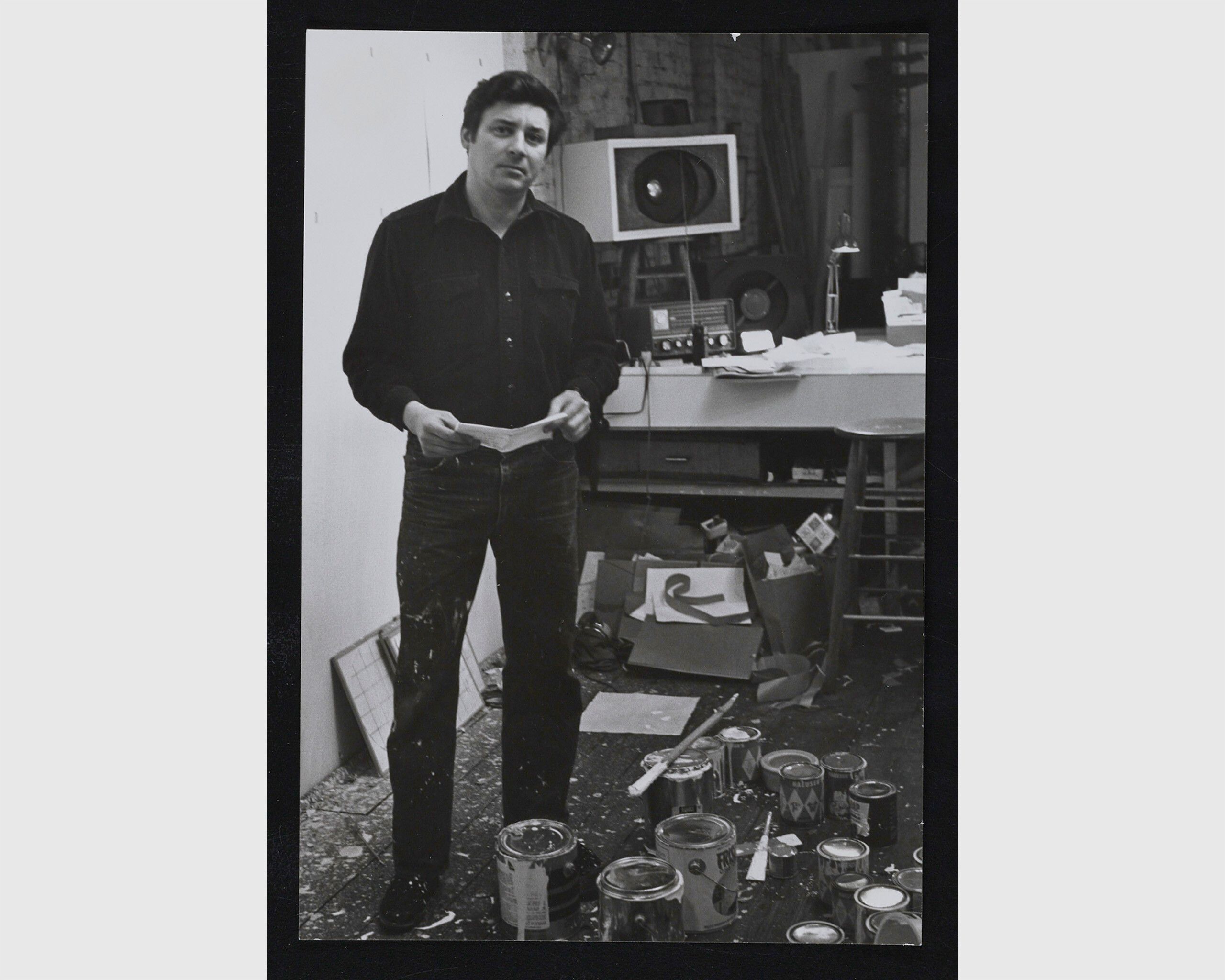 A black and white photo of Robert Ryman standing in his studio in New York in the late 1960s