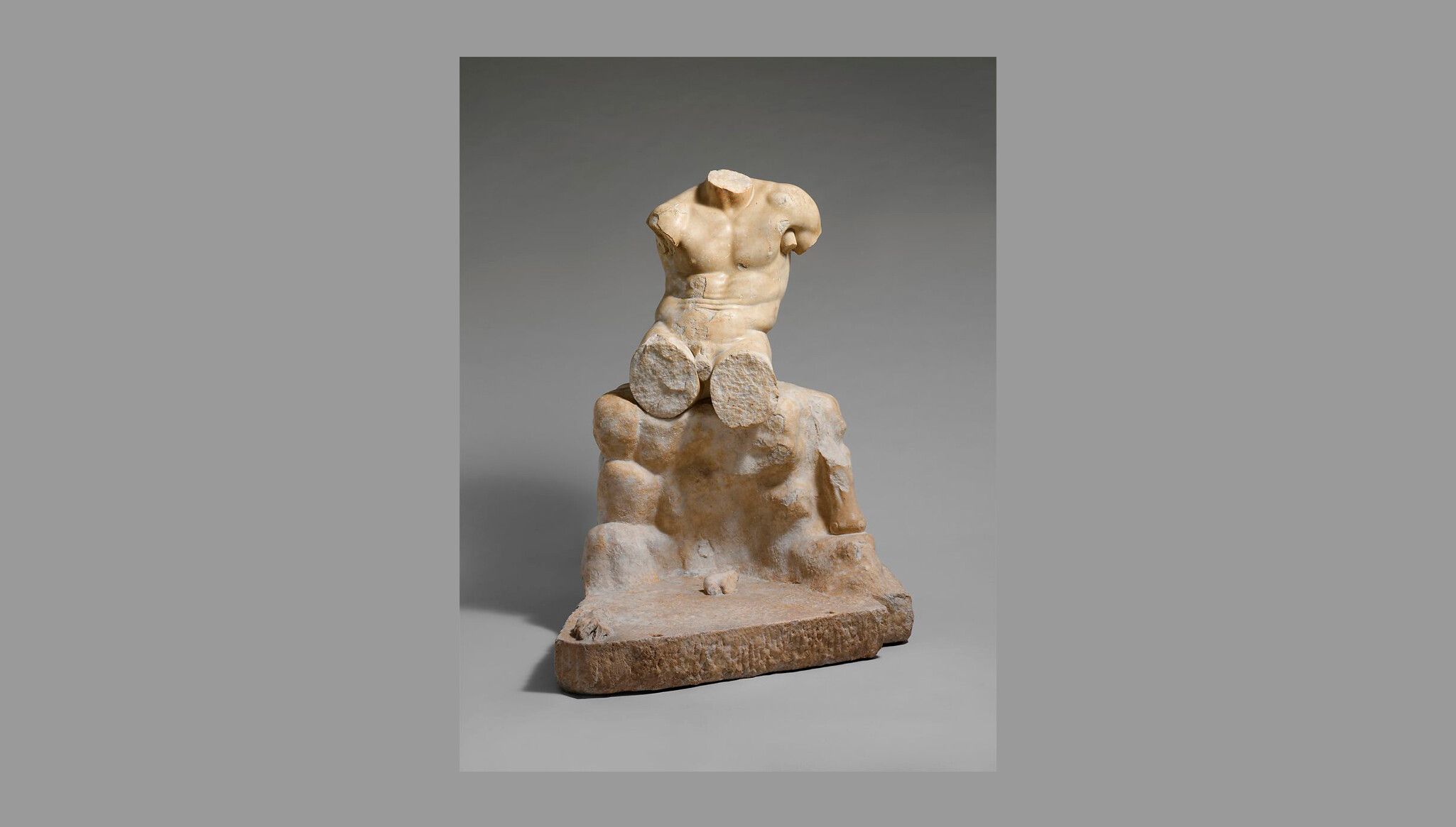 A Roman marble sculpture titled Torso of Hercules seated on a rock, dated 1st-2nd century AD.