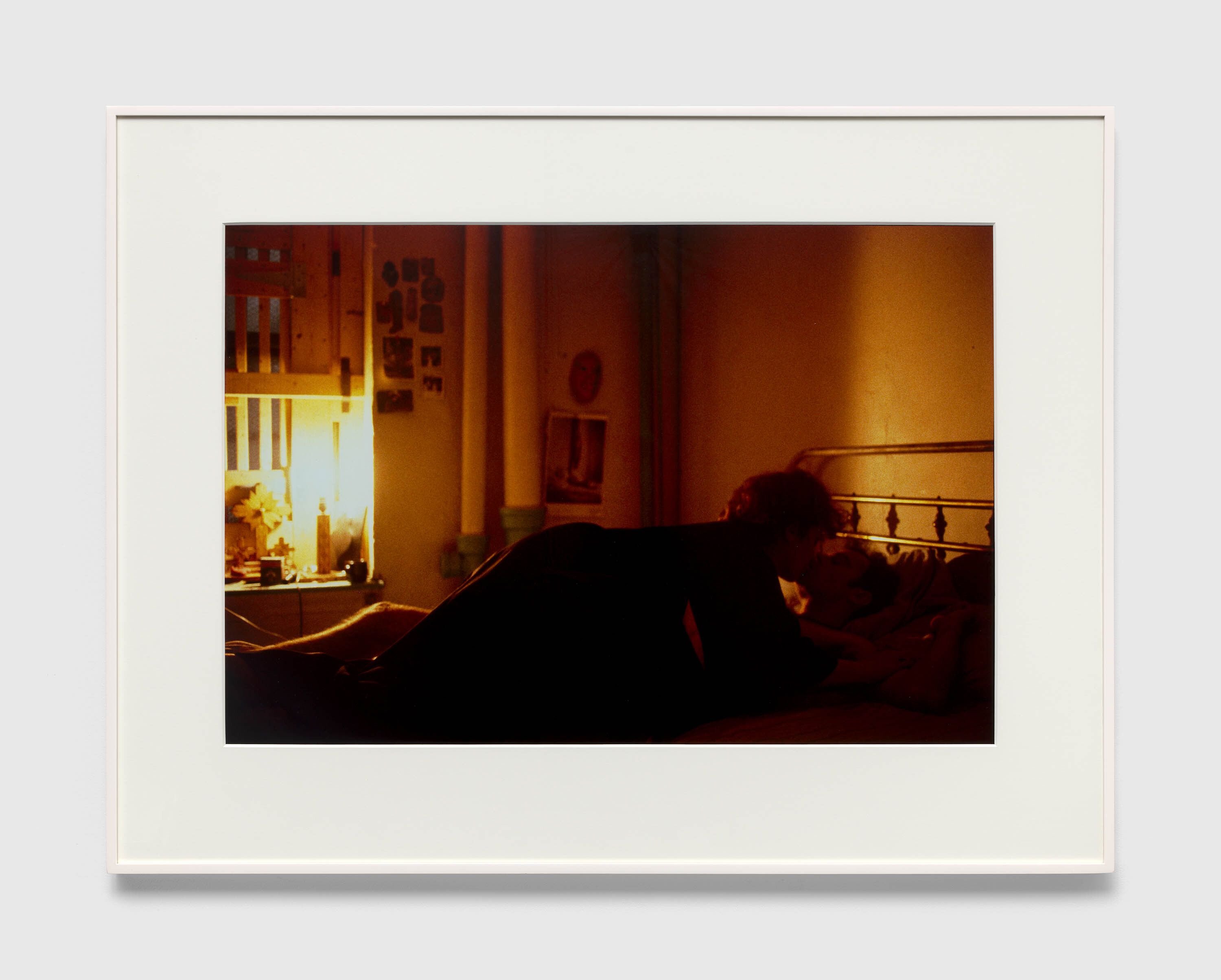 A photograph by Nan Goldin, titled Self-portrait on top of Brian, kissing, NYC, dated 1983.