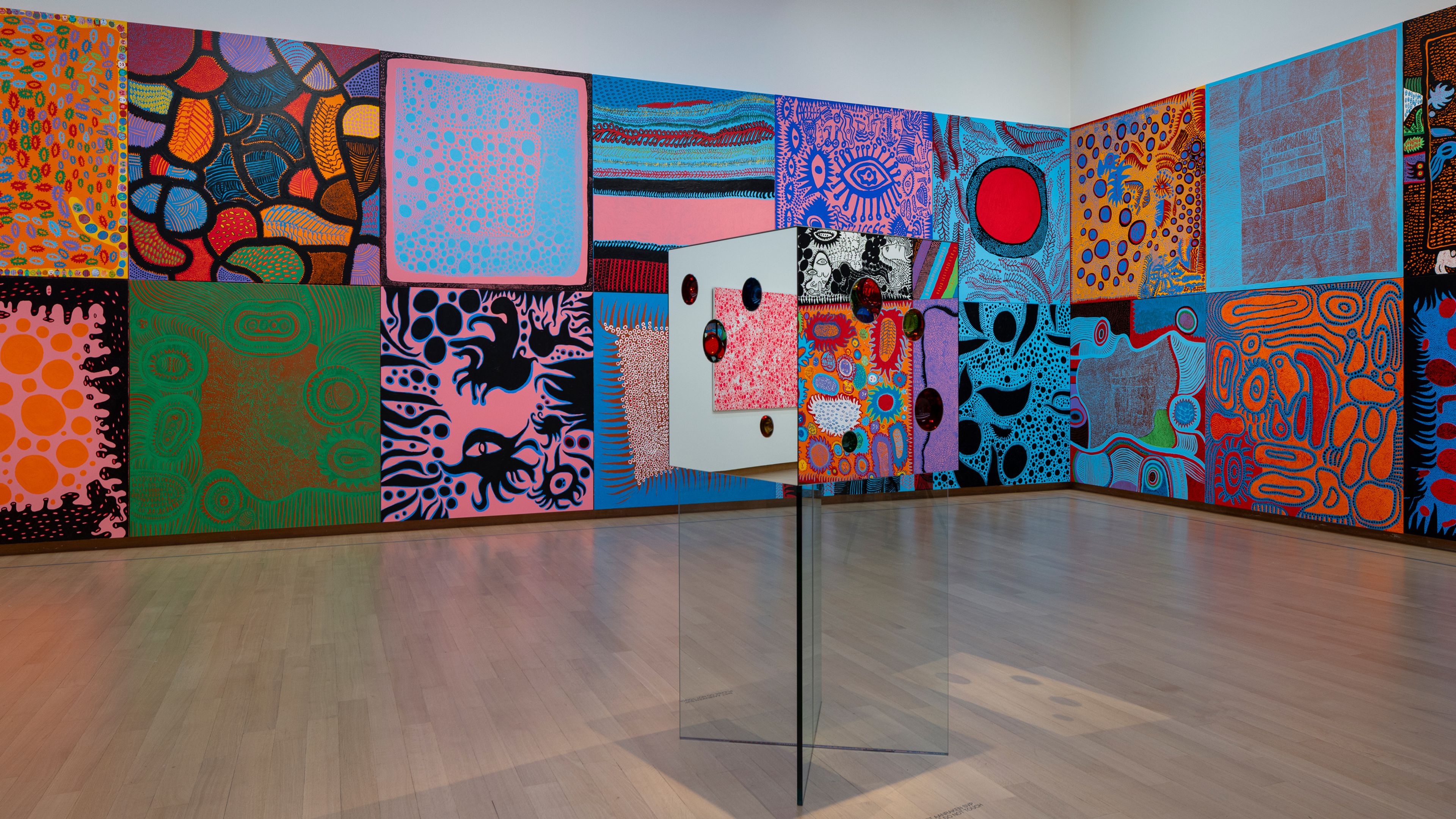 Installation view of Yayoi Kusama’s exhibition at the Stedelijk Museum Amsterdam, featuring colorful paintings and sculptures.