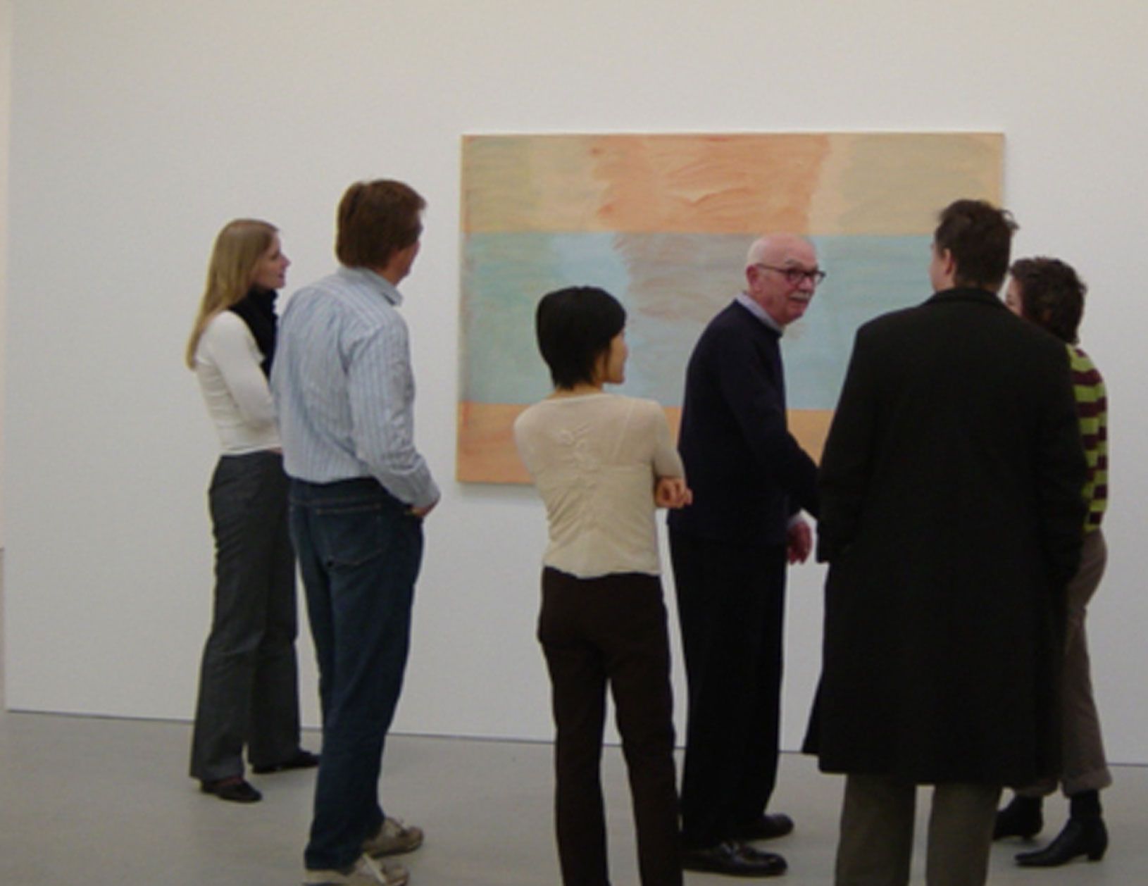 An image of Raoul De Keyser speaking in front of his painting.