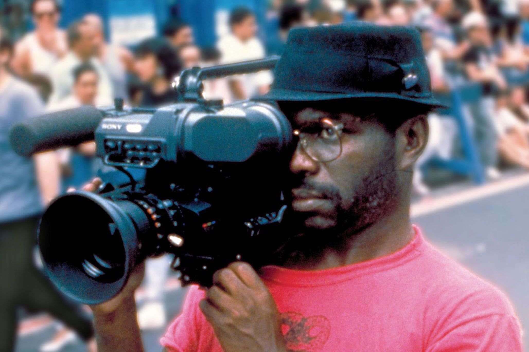 A portrait of the artist and film director Marlon Riggs holding a video camera.