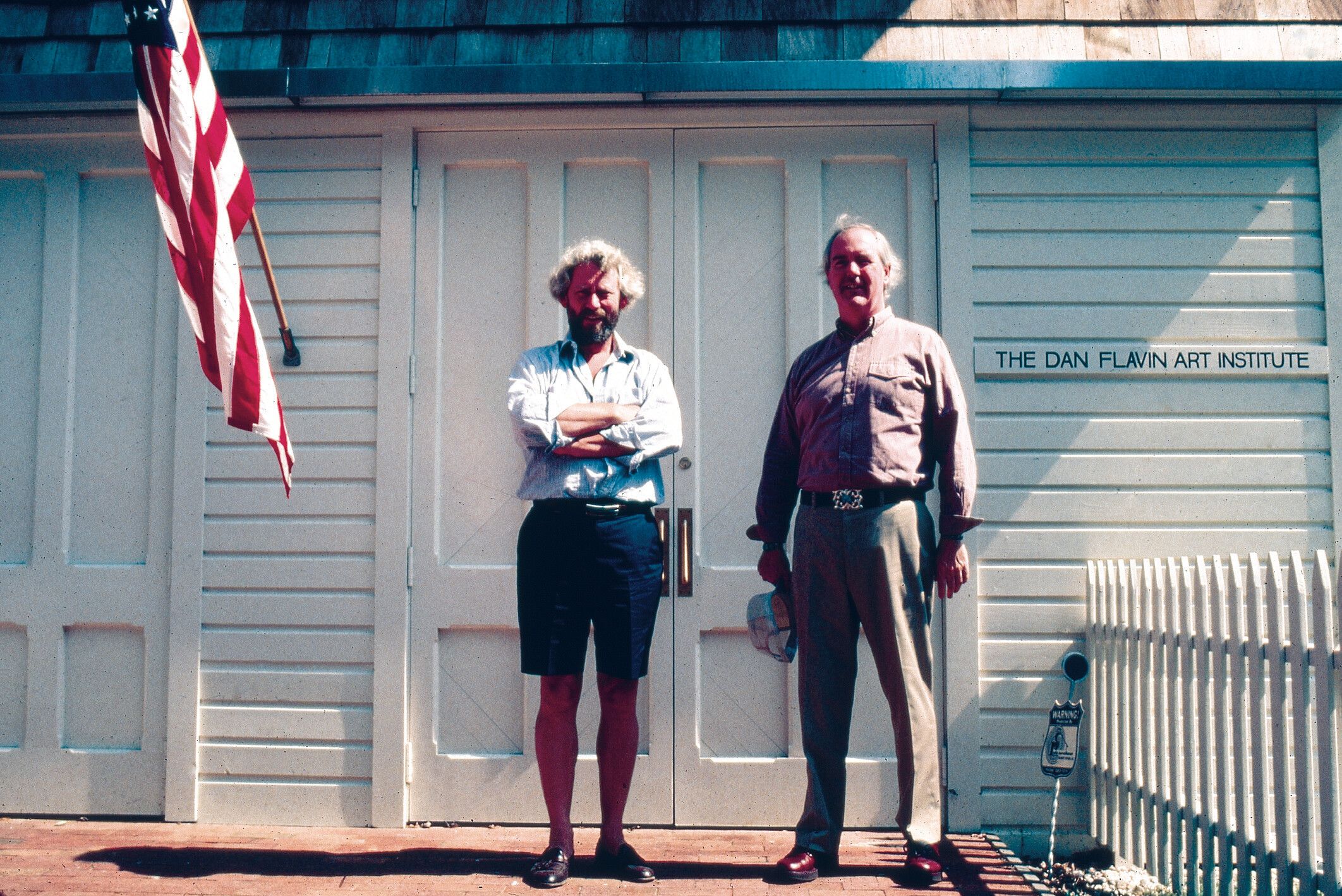 A photo of Donald Judd and Dan Flavin Outside the Dan Flavin Art Institute, Bridgehampton, New York, in 1983.