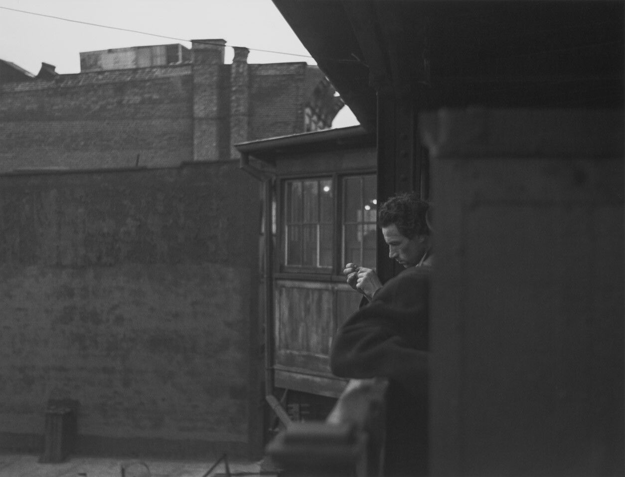 A silver gelatin print by Roy DeCarava, titled Man looking at hand, El station, dated 1988.
