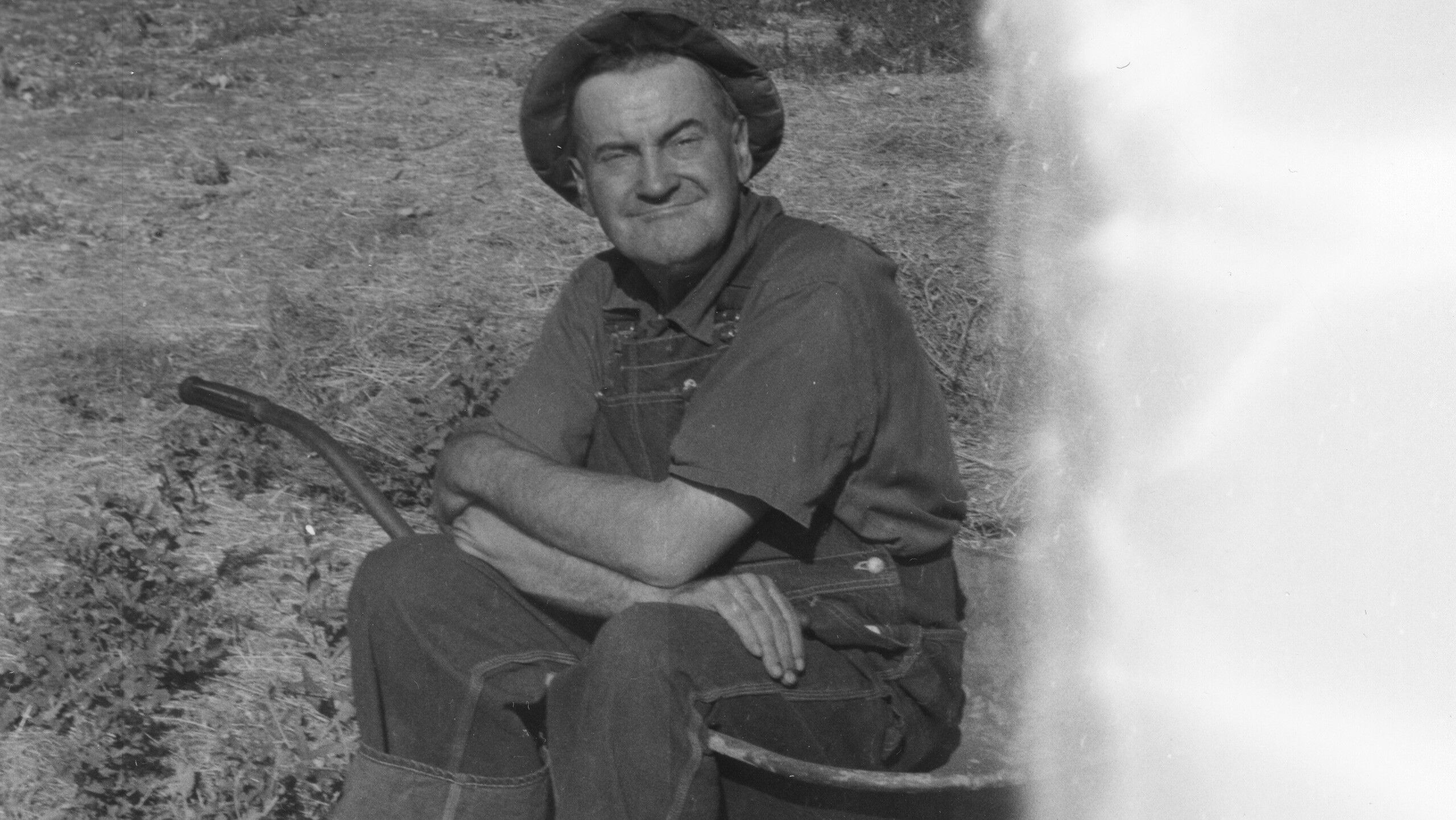 A photograph of James Castle sitting in a wheelbarrow by Bob Peach.