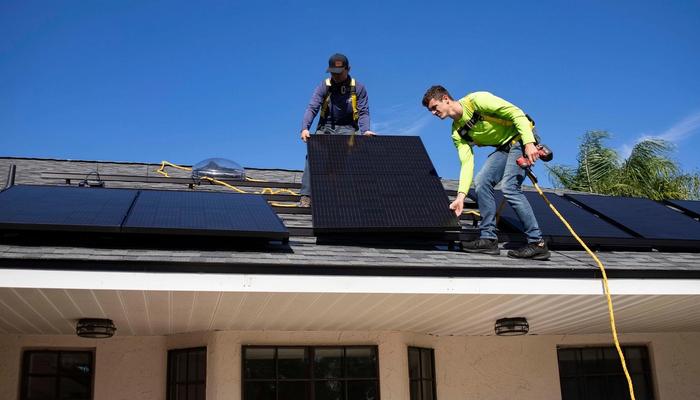 Two persons installing solar panels on a roof