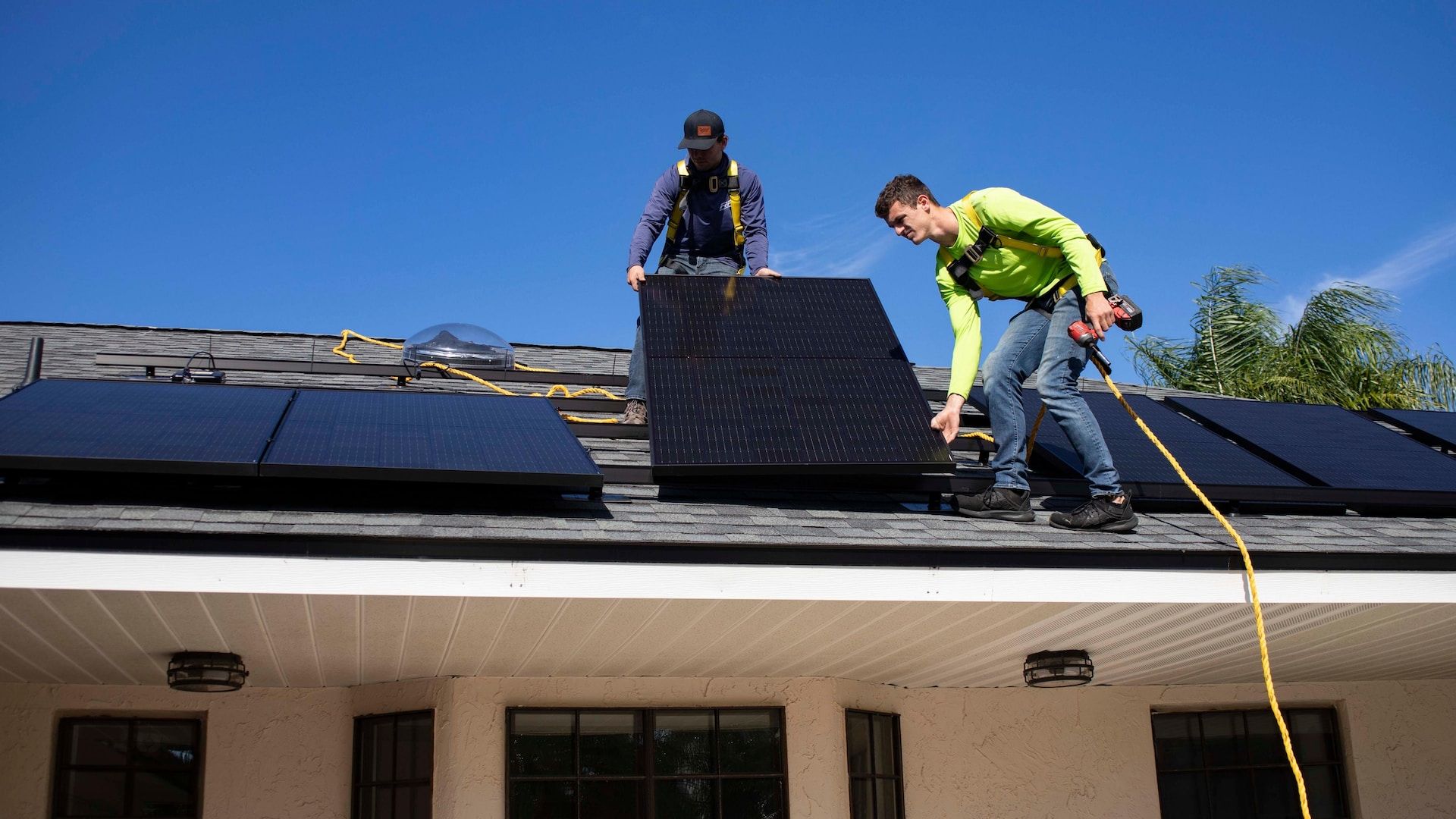 Two persons installing solar panels on a roof