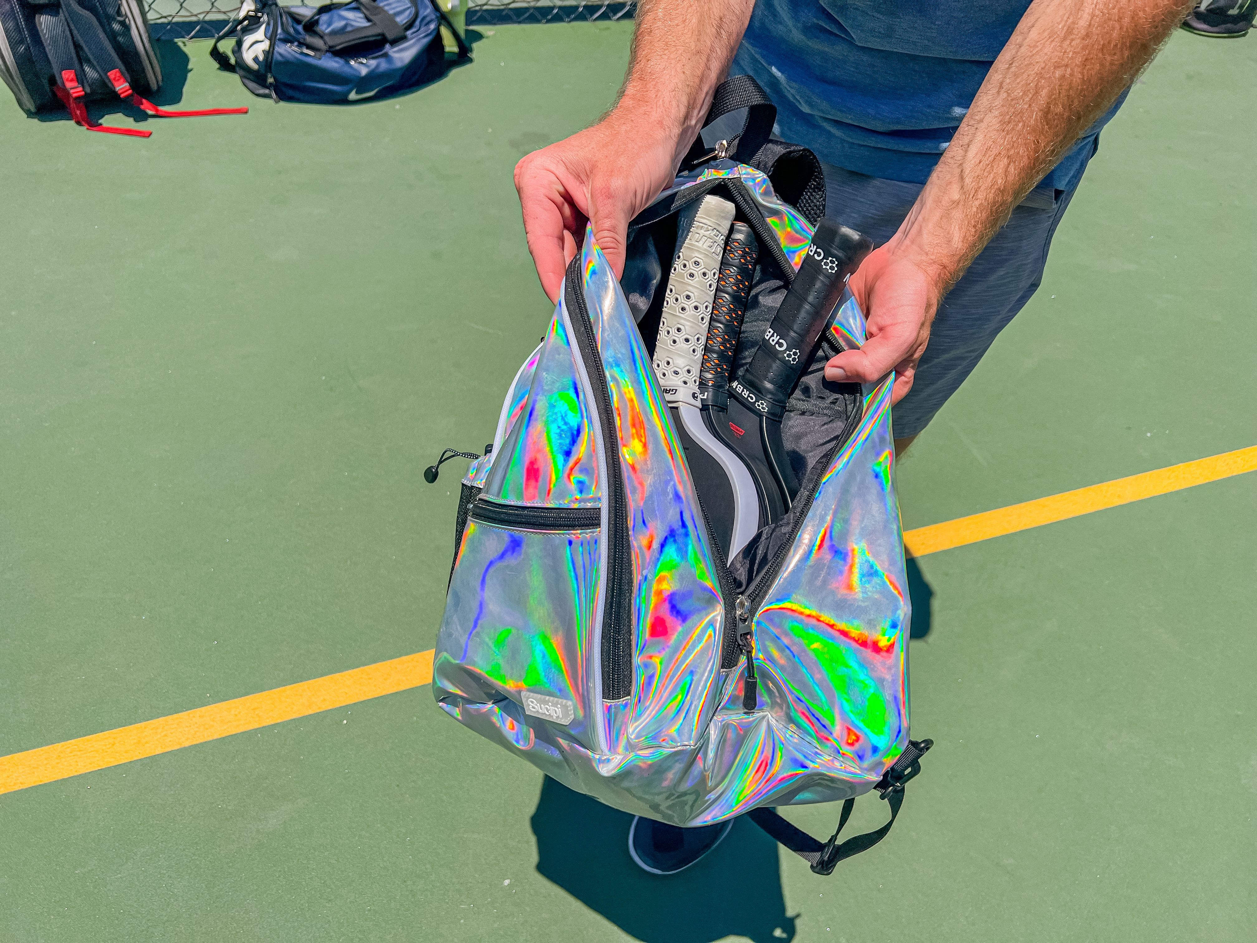 Brandon Mackie holding open the Sucipi Pickleball Backpack to show three pickleball paddles