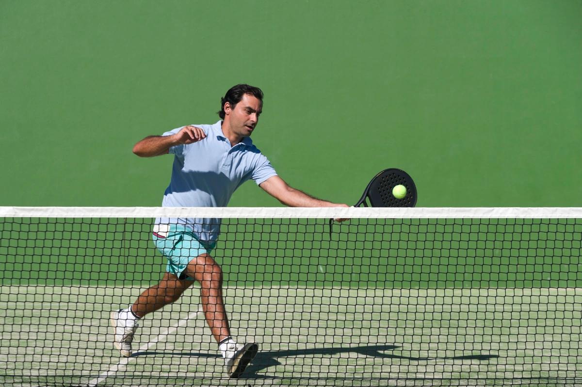 A paddle tennis player rushes to return a ball