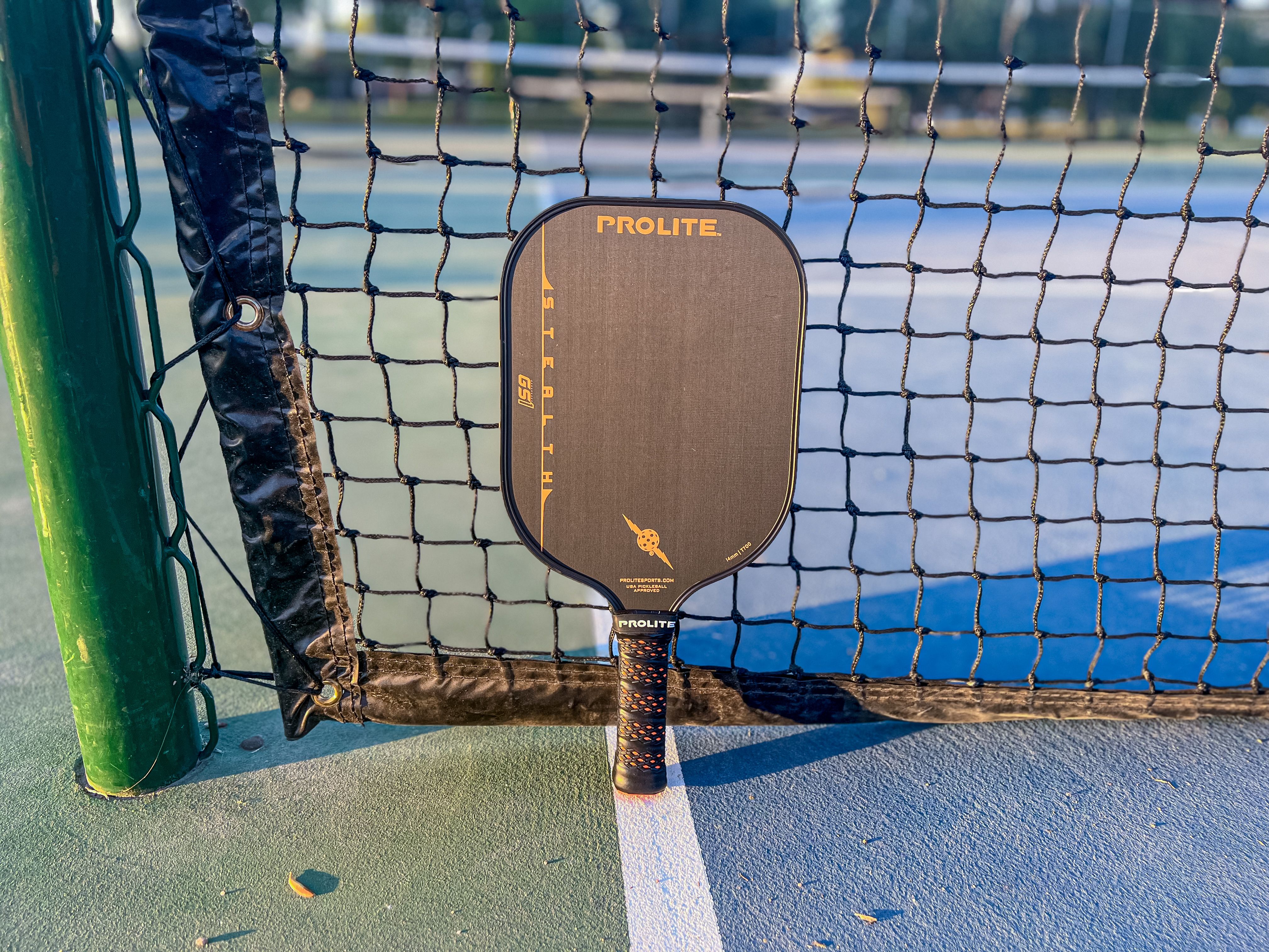 The PROLITE Stealth GS1 pickleball paddle resting against a net
