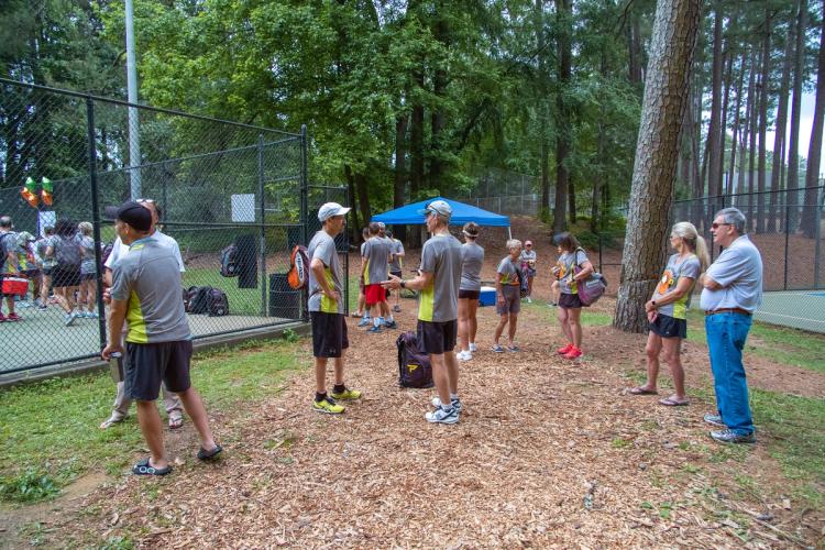 Group of people hanging around a park near pickleball courts