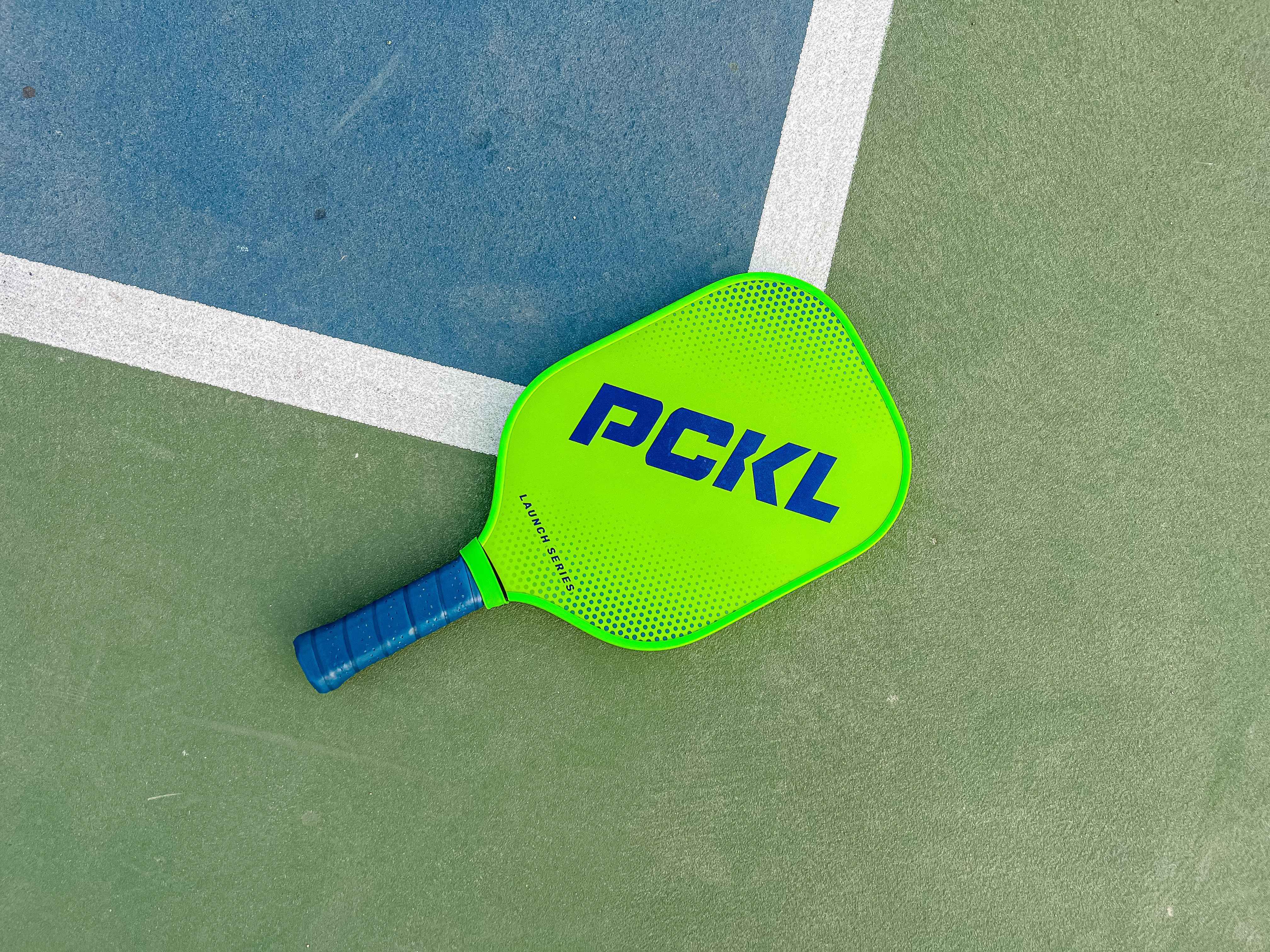 The PCKL Launch Series paddle placed at the edge of a pickleball court