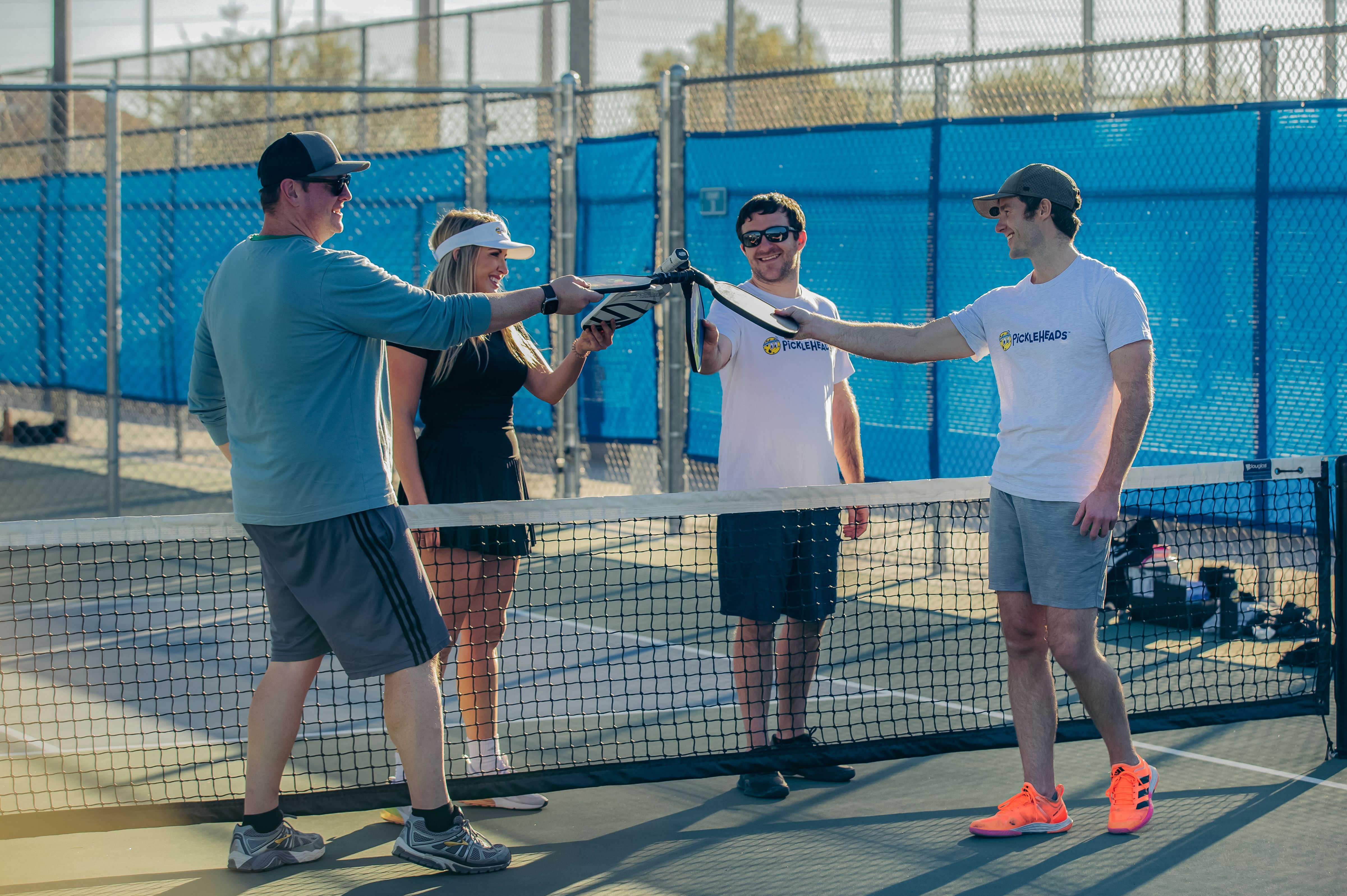 Four players celebrating a game on a pickleball court