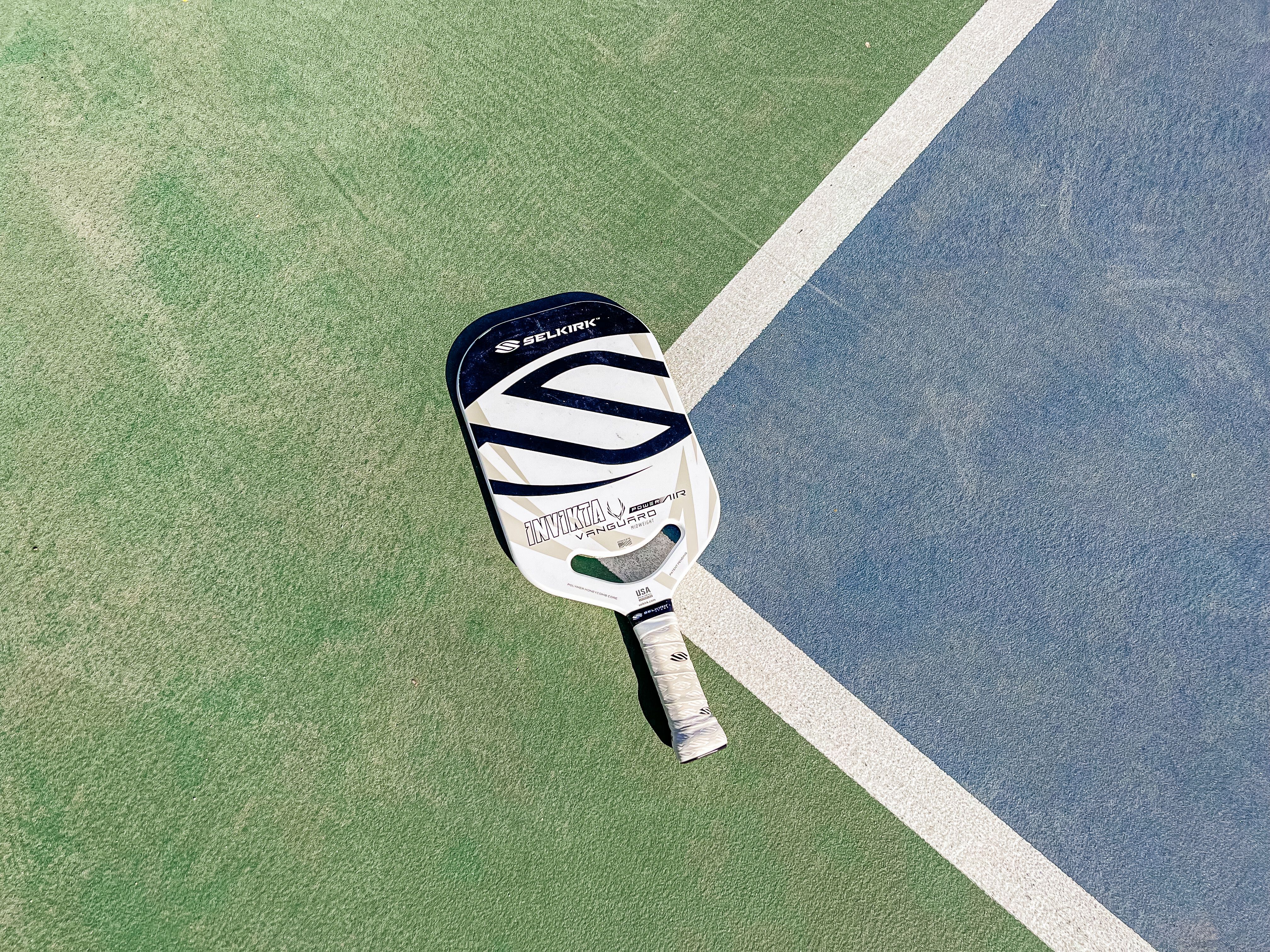 The Selkirk Vanguard Power Air Invikta paddle laid out on a pickleball court