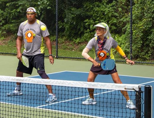 Players wearing pickleball team name shirts during a game