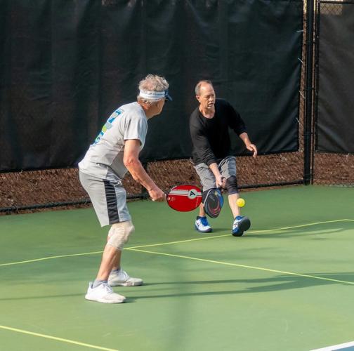 Player reaches for a ball in pickleball doubles