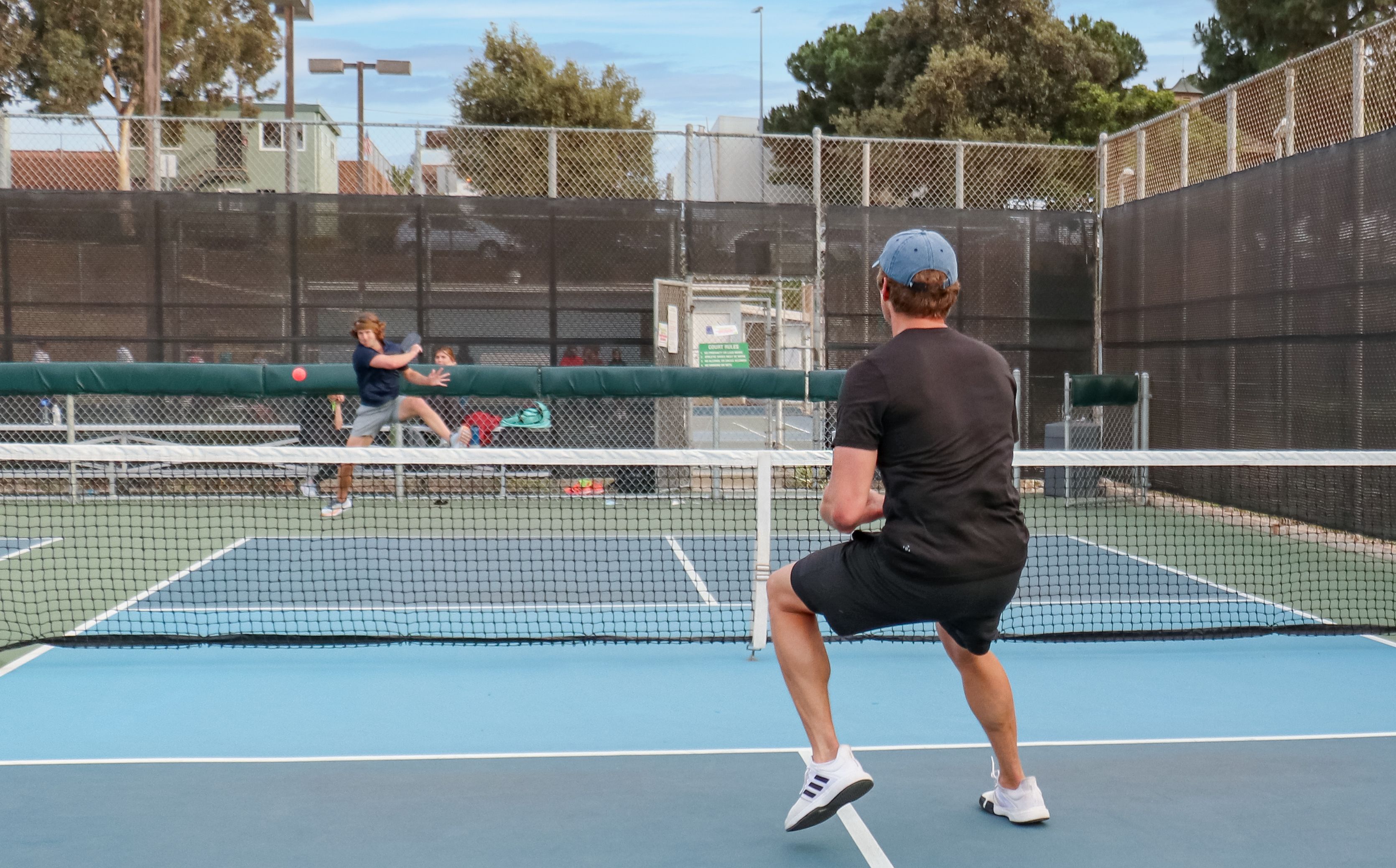 Two players in the middle of a game of singles pickleball