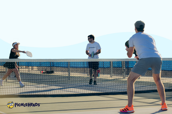 A group of players in the middle of a pickleball game on a sunny day
