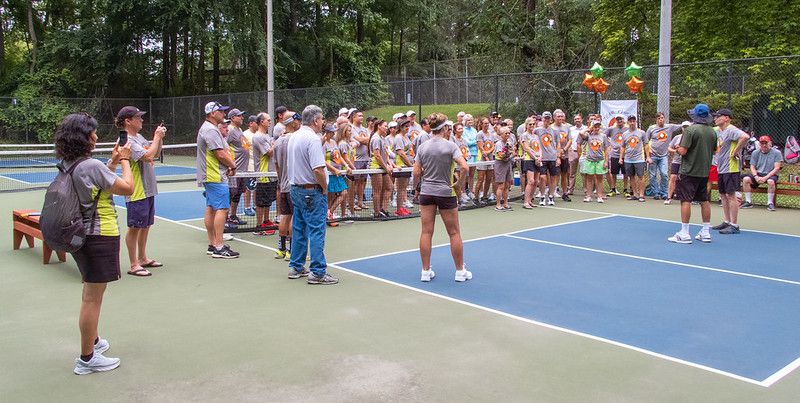 Players stand around a pickleball court at an open play session