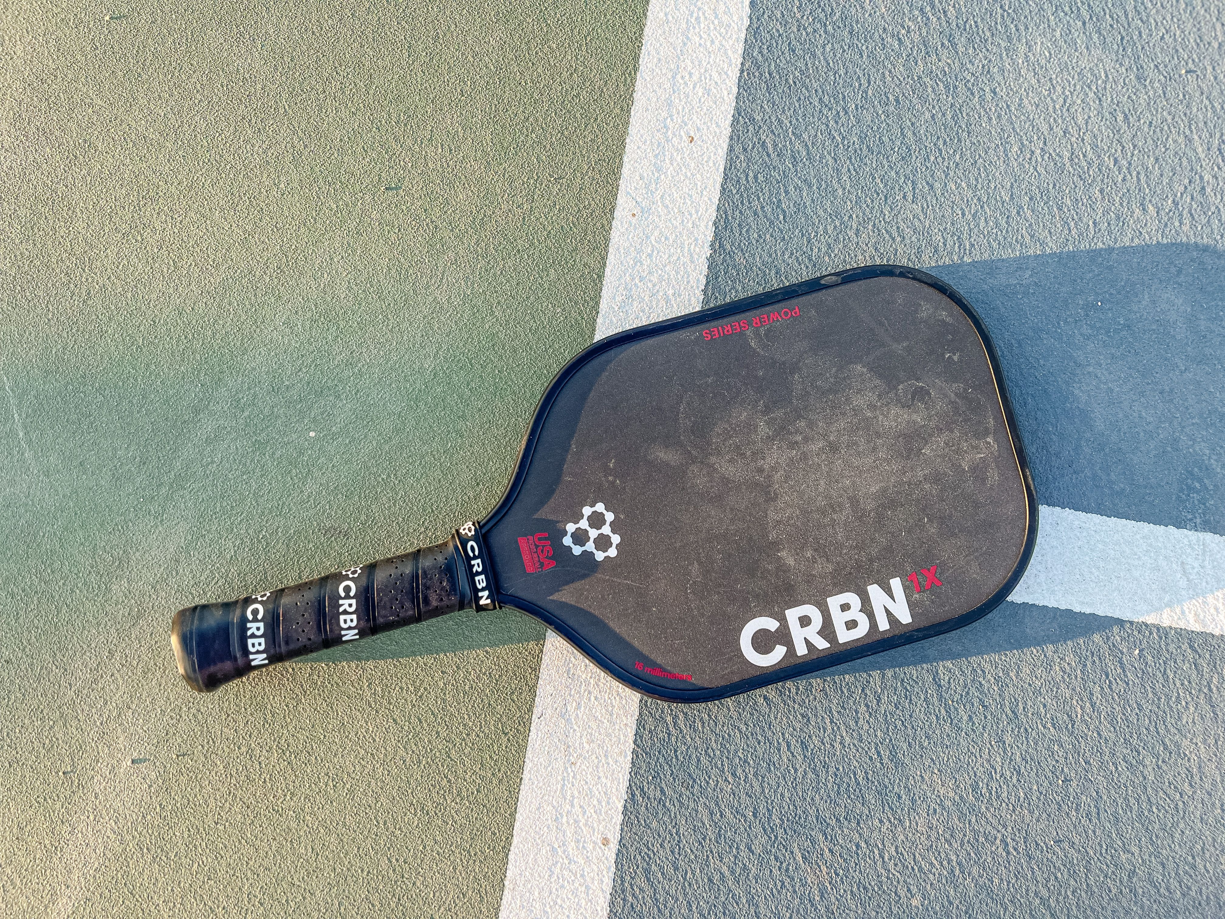 Photo of the CRBN-1X Power Series pickleball paddle placed on a court