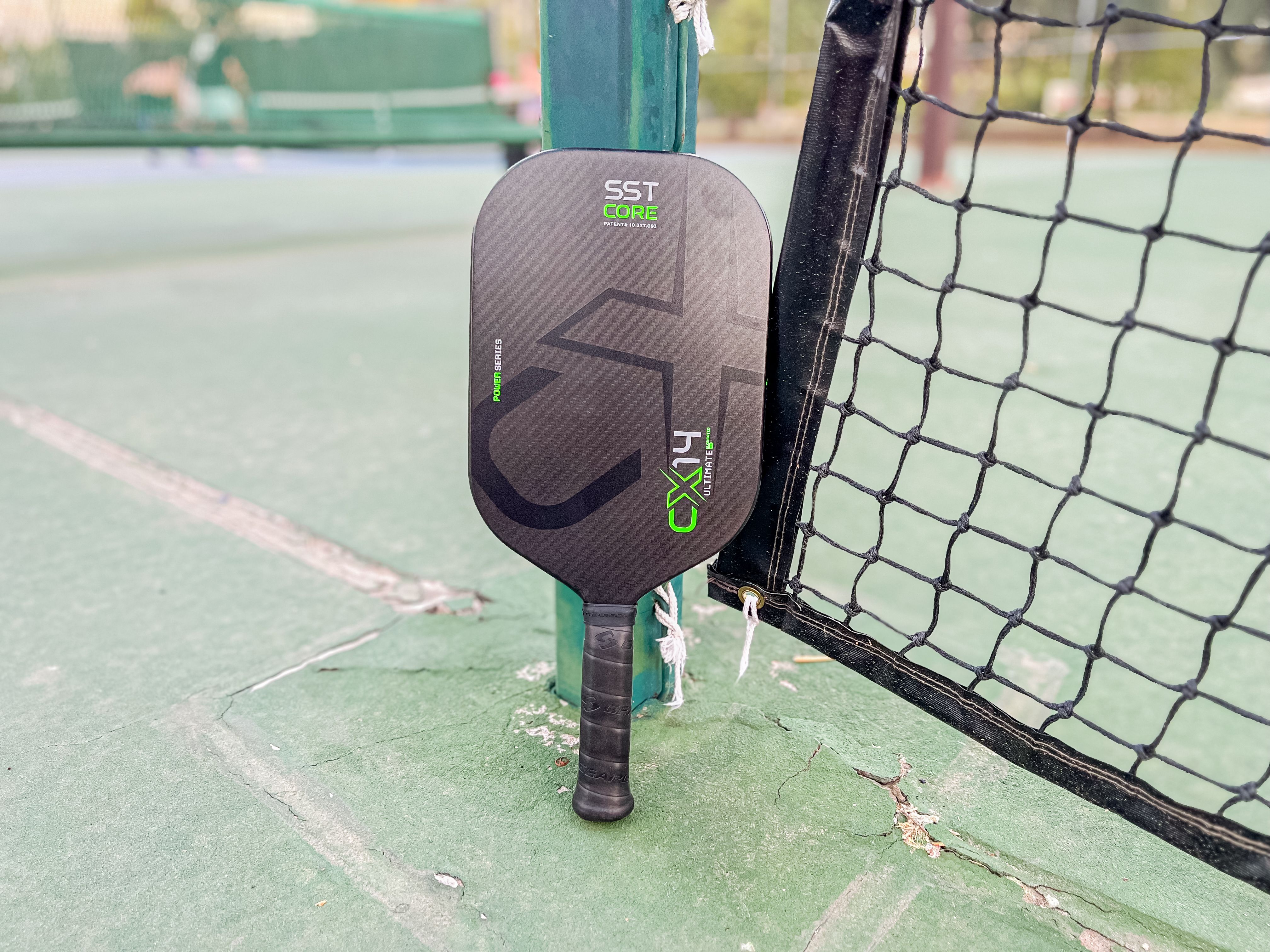 The Gearbox CX14E Ultimate Power pickleball paddle resting against a net
