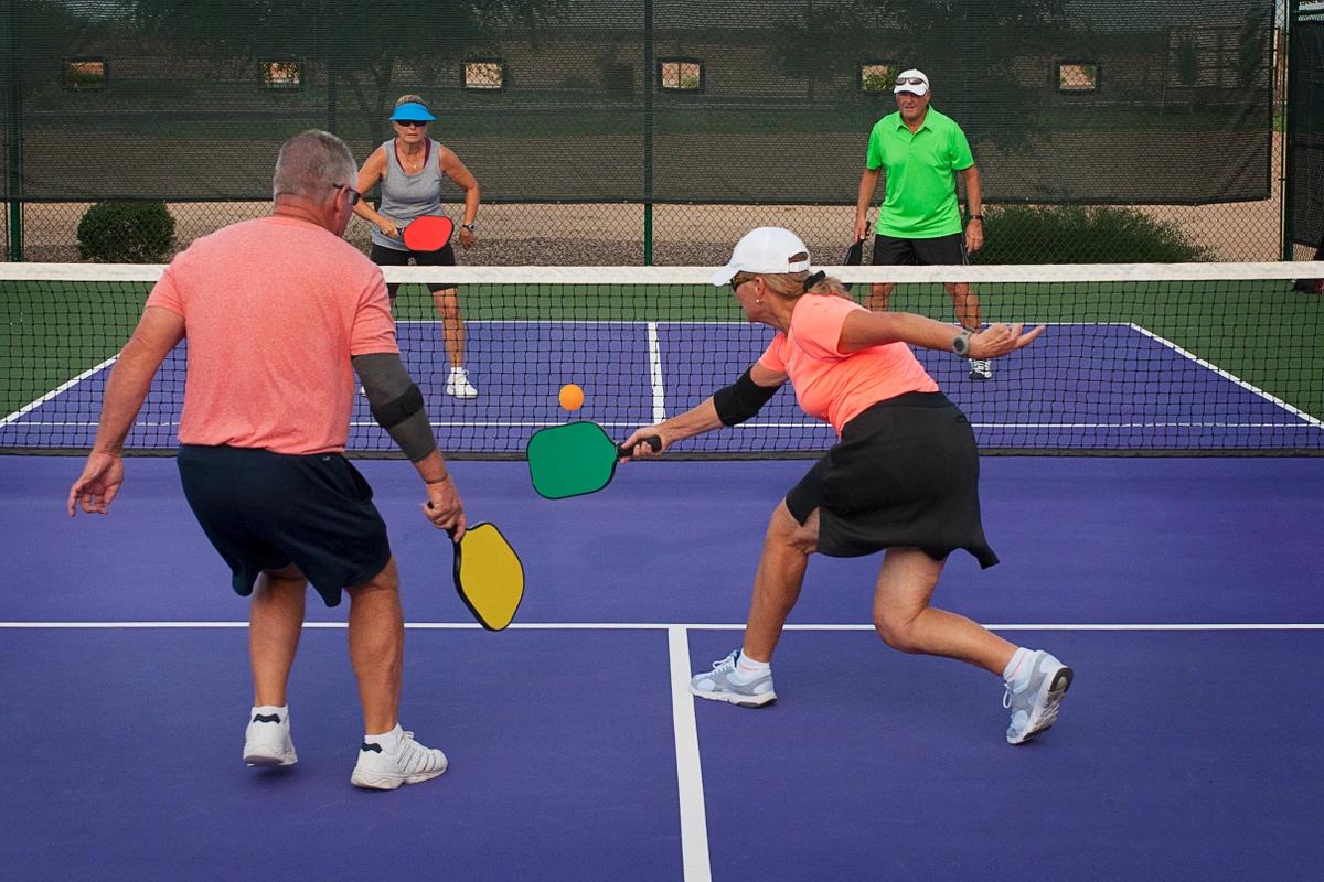 Four players at the kitchen line in a doubles pickleball game