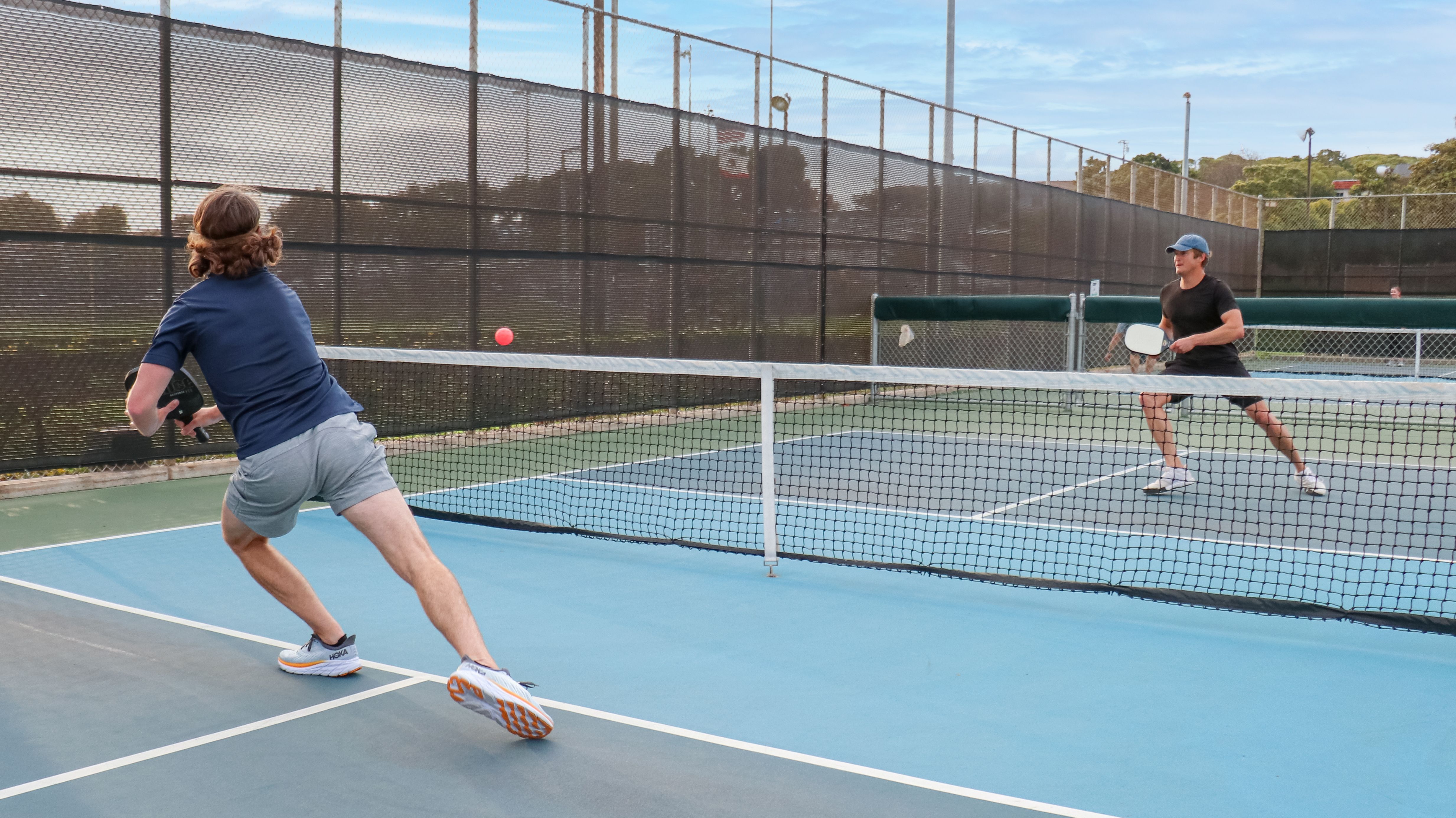 Players diving for shots in a singles pickleball game