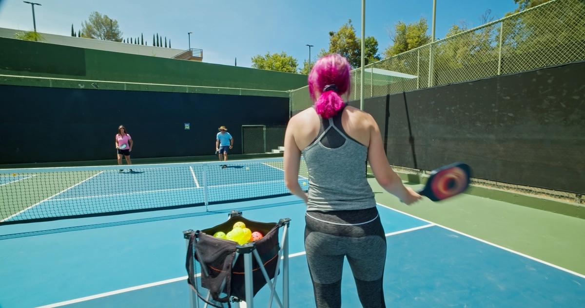 woman with pink hair playing pickleball