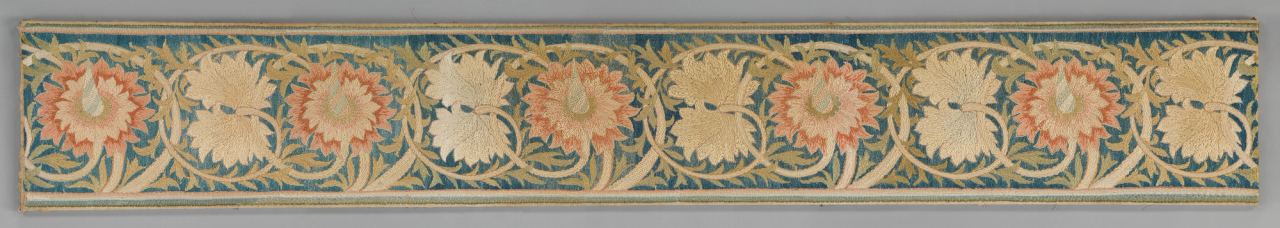 A long, narrow border of silk embroidery on a teal-blue ground: a repeating vine of curling cream stems with serrated olive-green leaves, carrying large salmon-pink flowers with pointed petals alternating with pairs of cream leaf shapes. Narrow cream and green stripes run along both edges.