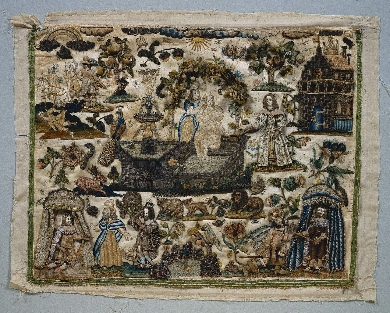 An unframed cream satin panel crowded with small embroidered figures and objects: padded men and women in seventeenth-century dress, two figures under canopies at the lower corners, two women by a pool and a stone terrace at the center, a stone building at right, a peacock, a deer, a lion and other animals, and raised leaves, trees and flowers.
