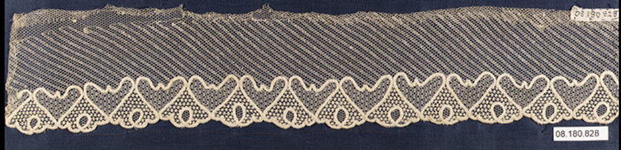 A strip of fine net whose even mesh runs in diagonal bands, with a scalloped border of heart-shaped motifs filled with smaller net patterns along the lower edge, on a dark blue mount.