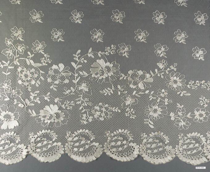 A wide flounce of fine sheer net, scattered with small floral sprigs above and with larger sprays of flowers and leaves, trailing stems and a scalloped border below, all in cream thread on gray.