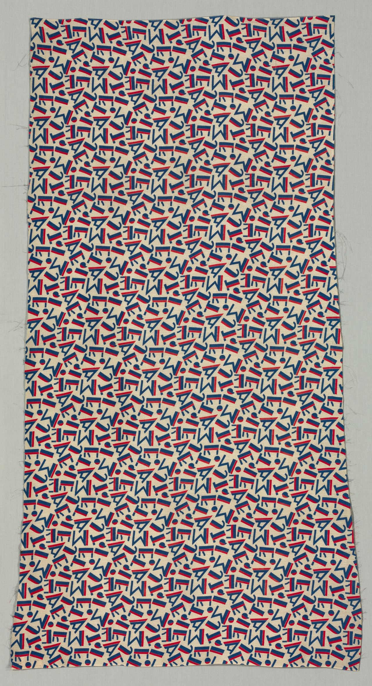 A length of cream fabric printed with scattered geometric letter shapes in blue, each bar edged with a red band; a few loose threads show along the cut edges, and up close the cream ground has a fine pebbled grain.