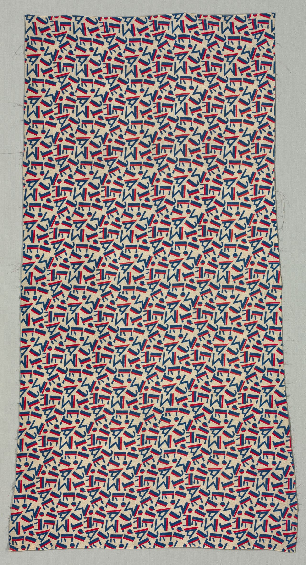 A length of cream fabric printed with scattered geometric letter shapes in blue, each bar edged with a red band; a few loose threads show along the cut edges, and up close the cream ground has a fine pebbled grain.