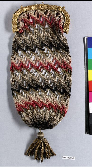 A crocheted purse seen from the front: diagonal stripes of grey, black, pink and red in an open stitch, a gilded metal frame at the top and a gold-coloured tassel hanging from the bottom.