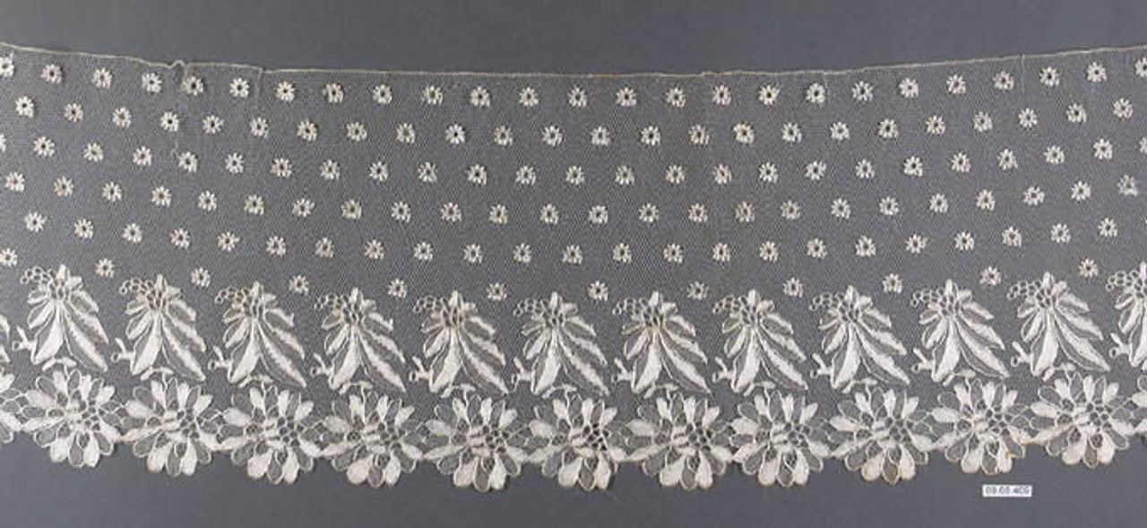 A wide border of sheer net with rows of small daisy-like dots above and a band of leaf sprays and large flowers in cream thread along a scalloped lower edge, on gray.