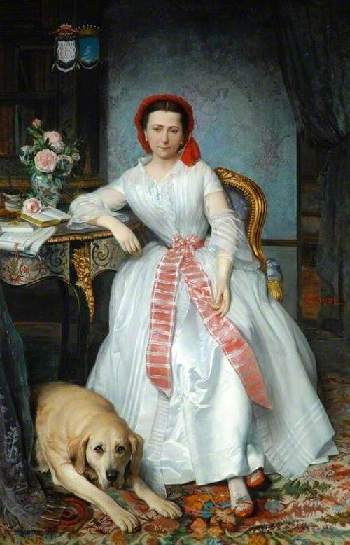 Full-length portrait of a young woman in a white silk gown with a red-and-white striped sash and a red cap, seated beside a gilt-edged table with a book, papers and a vase of roses, a large pale dog lying at her feet on a patterned carpet.