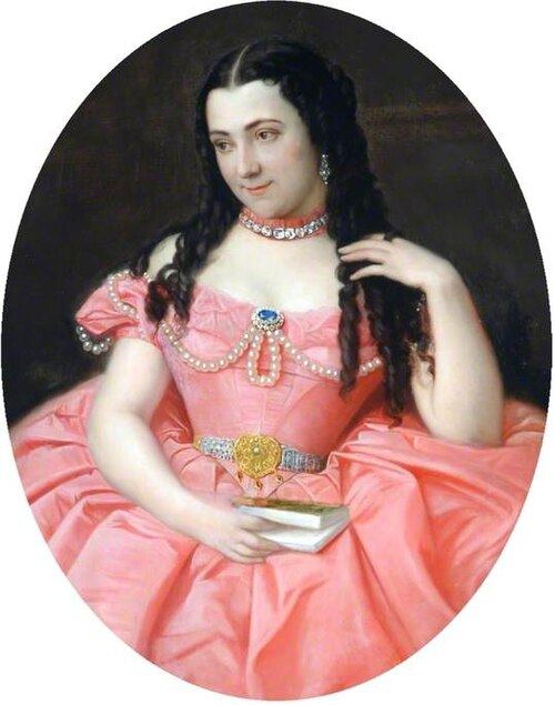 Oval portrait of a dark-haired woman in a pink off-the-shoulder gown trimmed with pearls, wearing a jeweled choker and a wide jeweled belt, holding a small book in her lap and looking to one side.