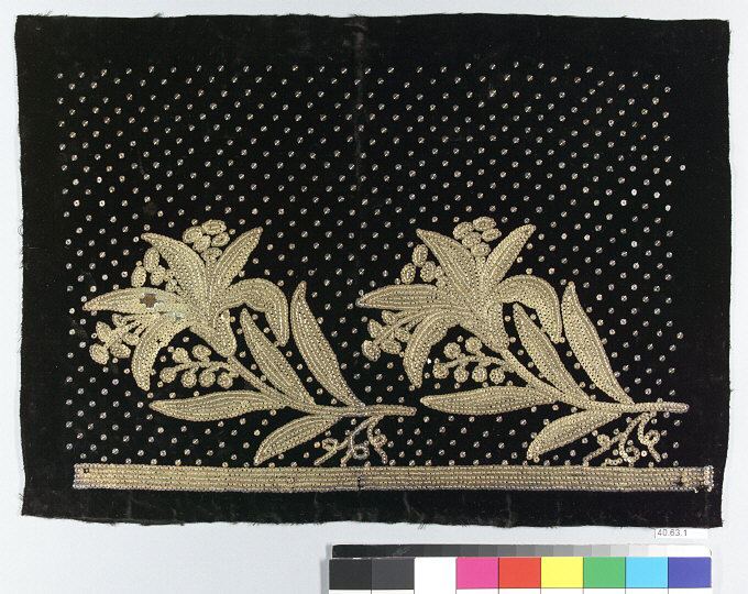 A panel of dark velvet scattered with tiny gold sequins in a regular dotted grid, with two sprays of flowers and leaves in denser gold sequins above a braided border.